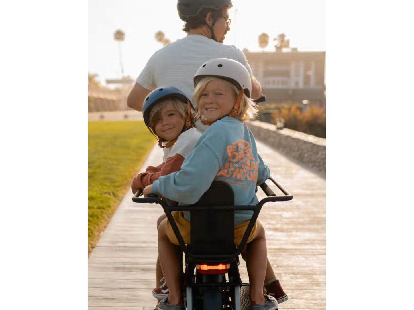 Aventon Abound Male rider with two kiddos in the cargo accessory option