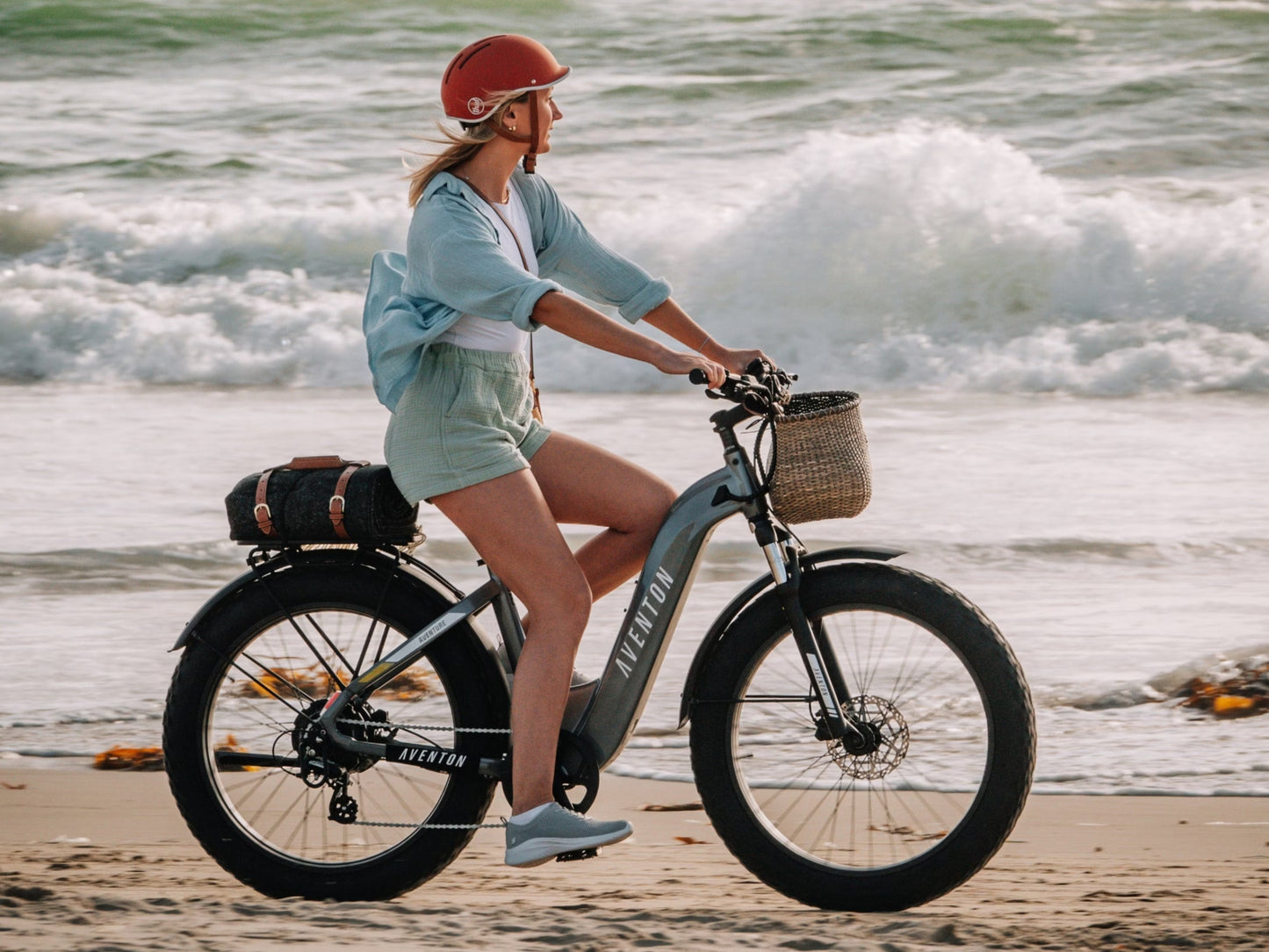 Aventon Aventure 3 Step-through Hardtail All Terrain Electric Bike Woman riding along beach shore