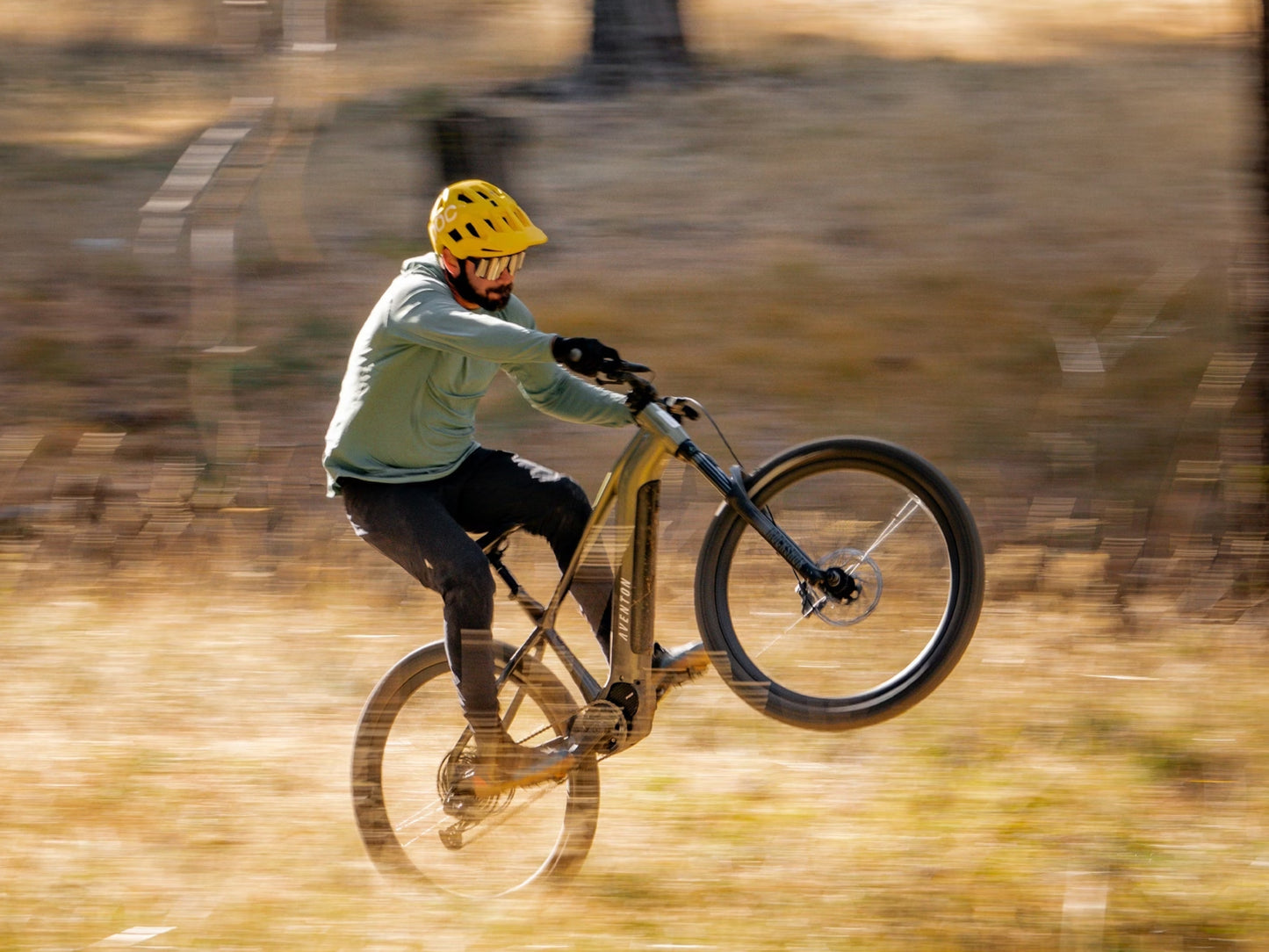 Aventon Ramblas Hardtail eMTB Male rider in a field, popping a wheelie