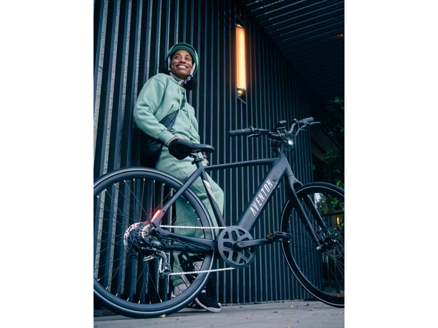 Aventon Soltera 2.5 Road /commuter Urban eBike Matte midnight black
Lifestyle - Woman prepared for a night ride leaning up against corrugated metal wall