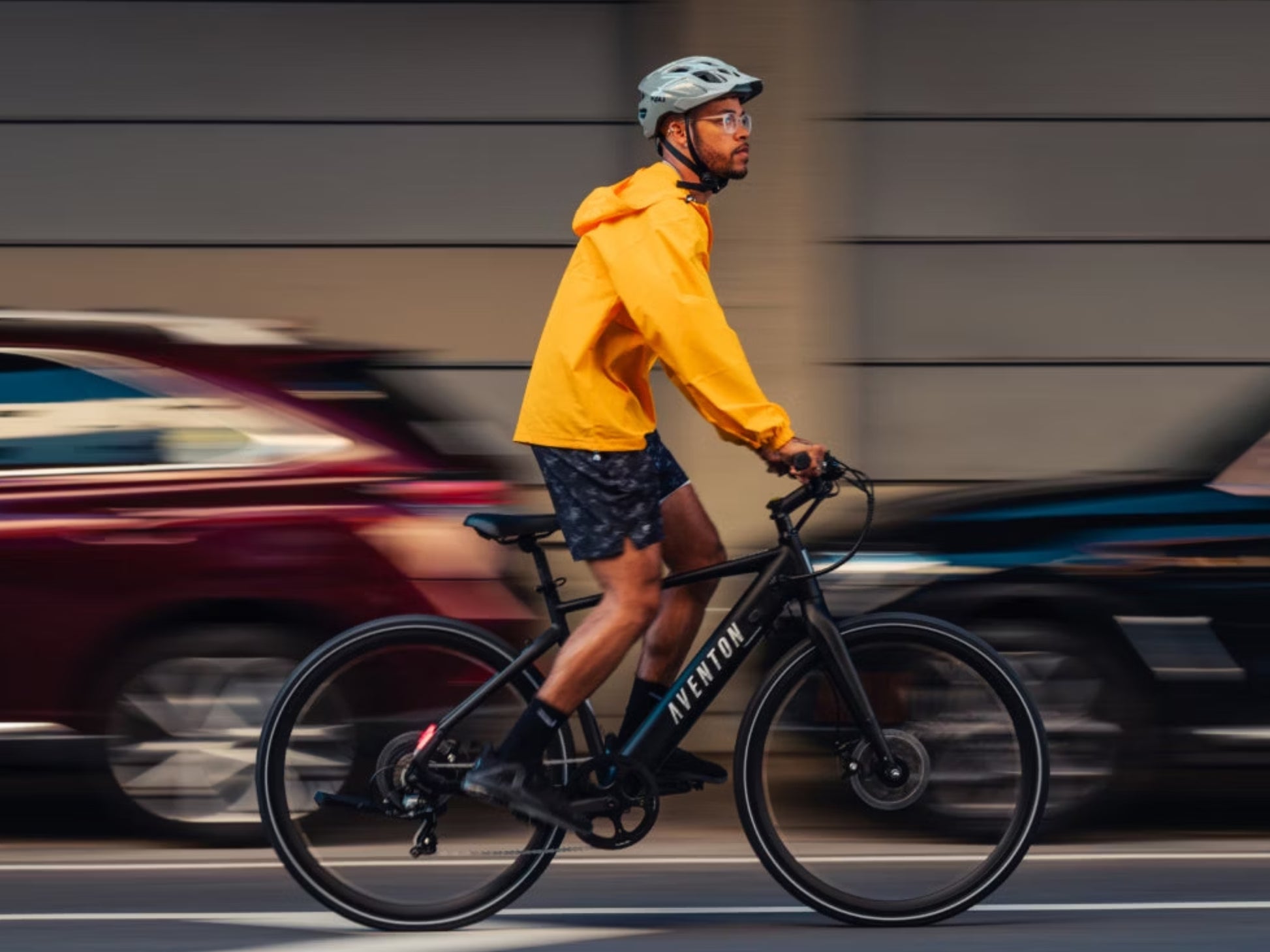 Aventon Soltera 2. Road /commuter Urban eBike Matte midnight black Rider On urban street wearing shorts and yellow jacket
