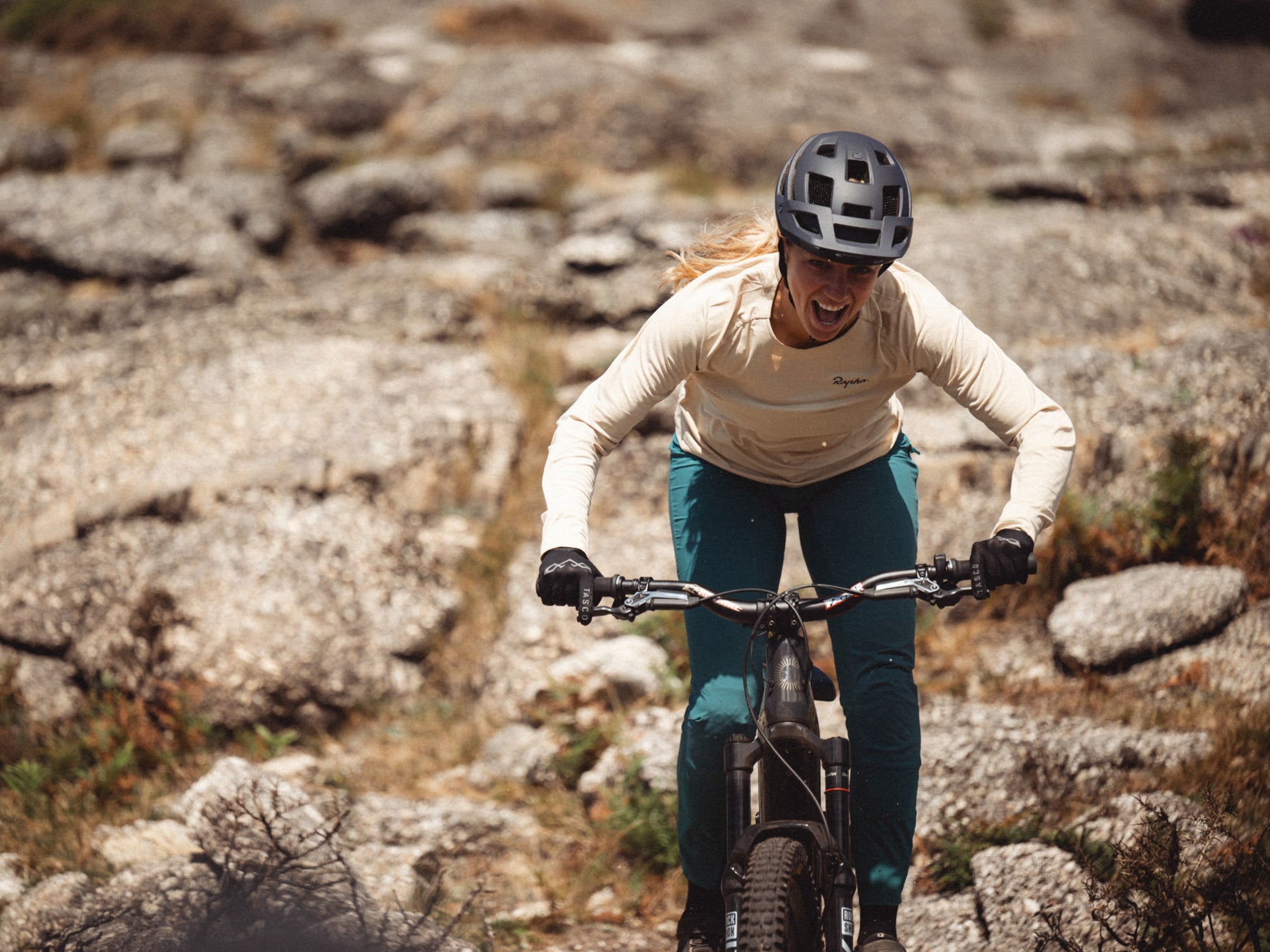 Cannondale Moterra SL Dual suspension eMTB Female Rider with a huge smile going over rocky terrain