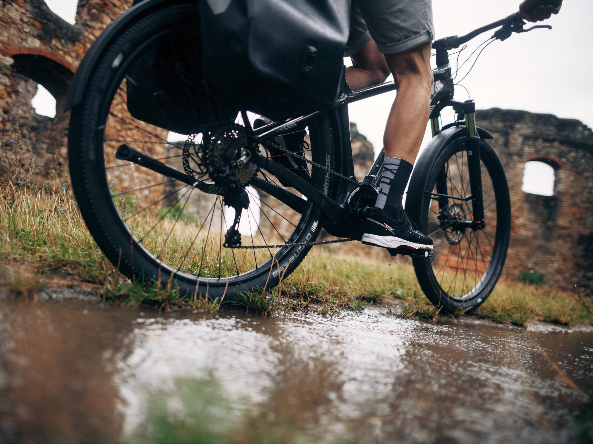 Cannondale Tesoro Carbon Electric bike High Speed Road / commuter Bike closeup on wet paved road. Old brick walls in background
