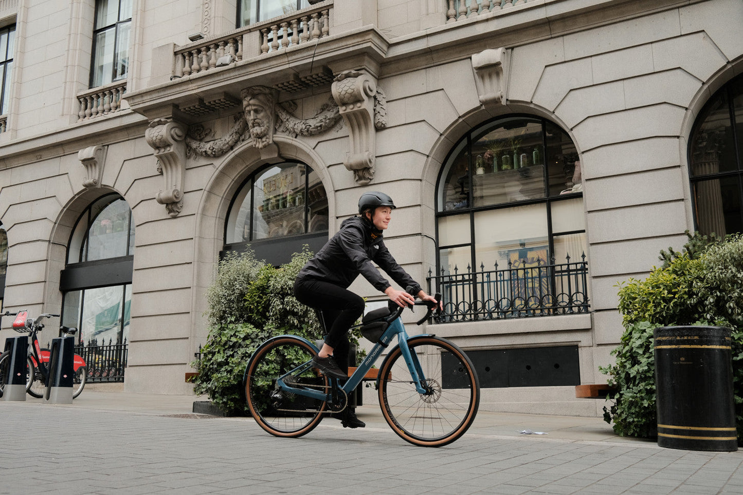 Mondraker Dusty SX Gravel Urban Cross Electric bike Woman riding on brick road past city building