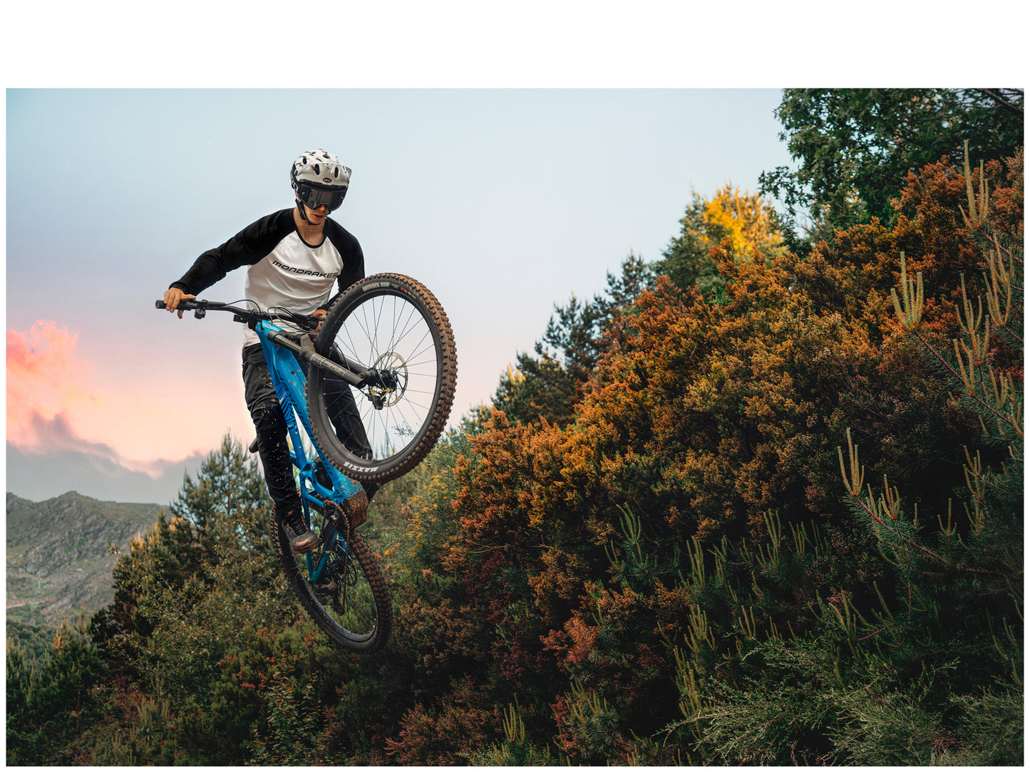 Mondraker Sly R Marlin blue eMTB Lifestyle Rider getting air over fall colored trees