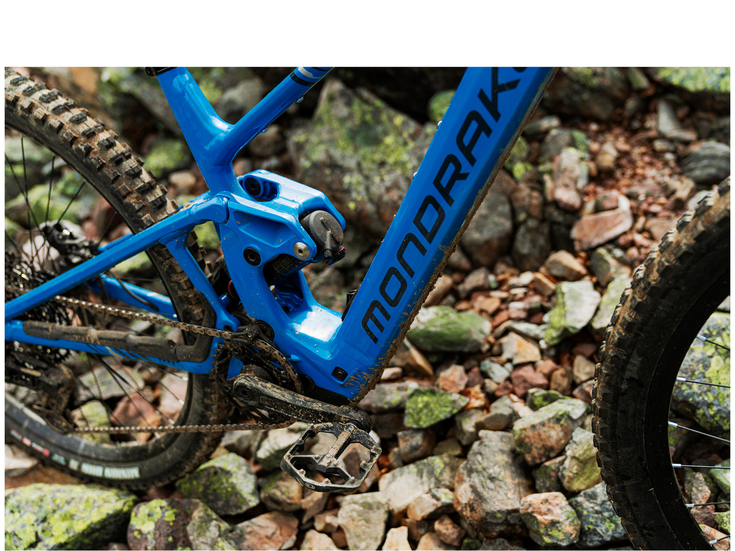Mondraker Sly R eMTB Marlin blue / racing silver / obsidian grey Lifestyle Muddy rear traiangle, pedals, rear shock and motor view