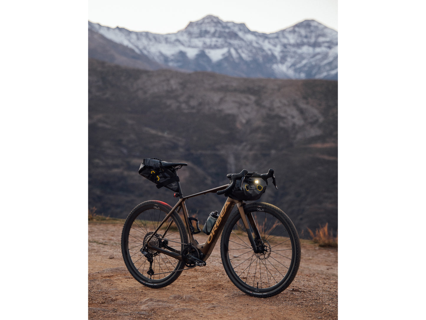 Orbea Denna Gravel Road / commuter eBike. Lifestyle parked on dirt path with snow capped mountain background