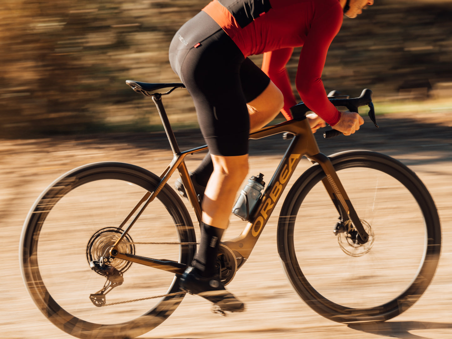 Orbea Denna Gravel Road / commuter eBike Rider in red and black kit on dirt path