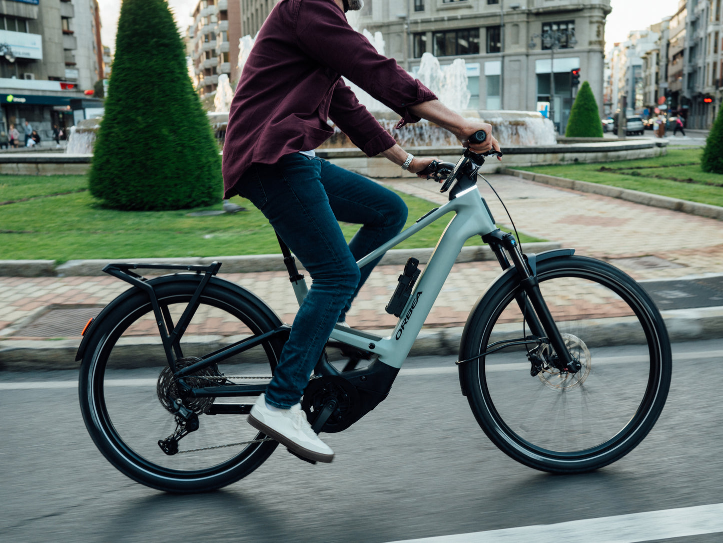 Orbea Muga 28MPH Mid step Road commuter Lifestyle of a Man commuter on a city street with city buildings in the background.