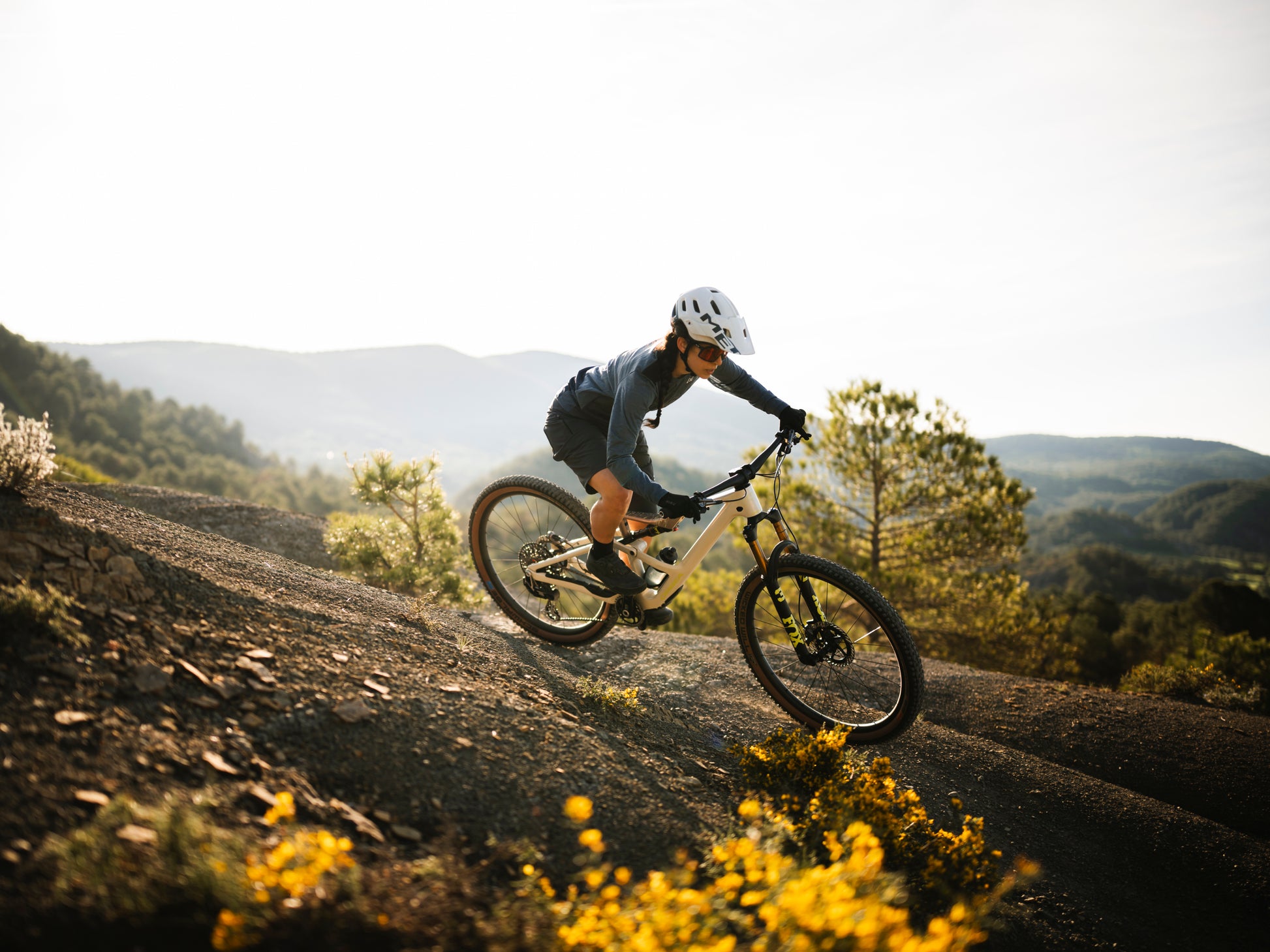 Orbea Occam SL Full Suspension Mountain bike, Lifestyle. Rider on dirt path with the sun shining on the hills