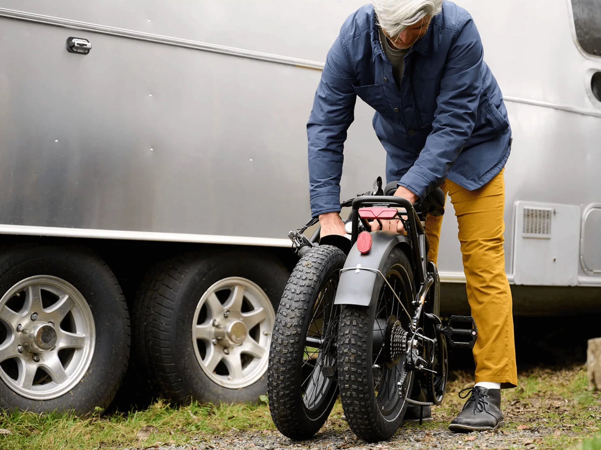 Rad Power RadExpand™ 5 Electric Folding Bike. Man folding the bike with a RV in the background