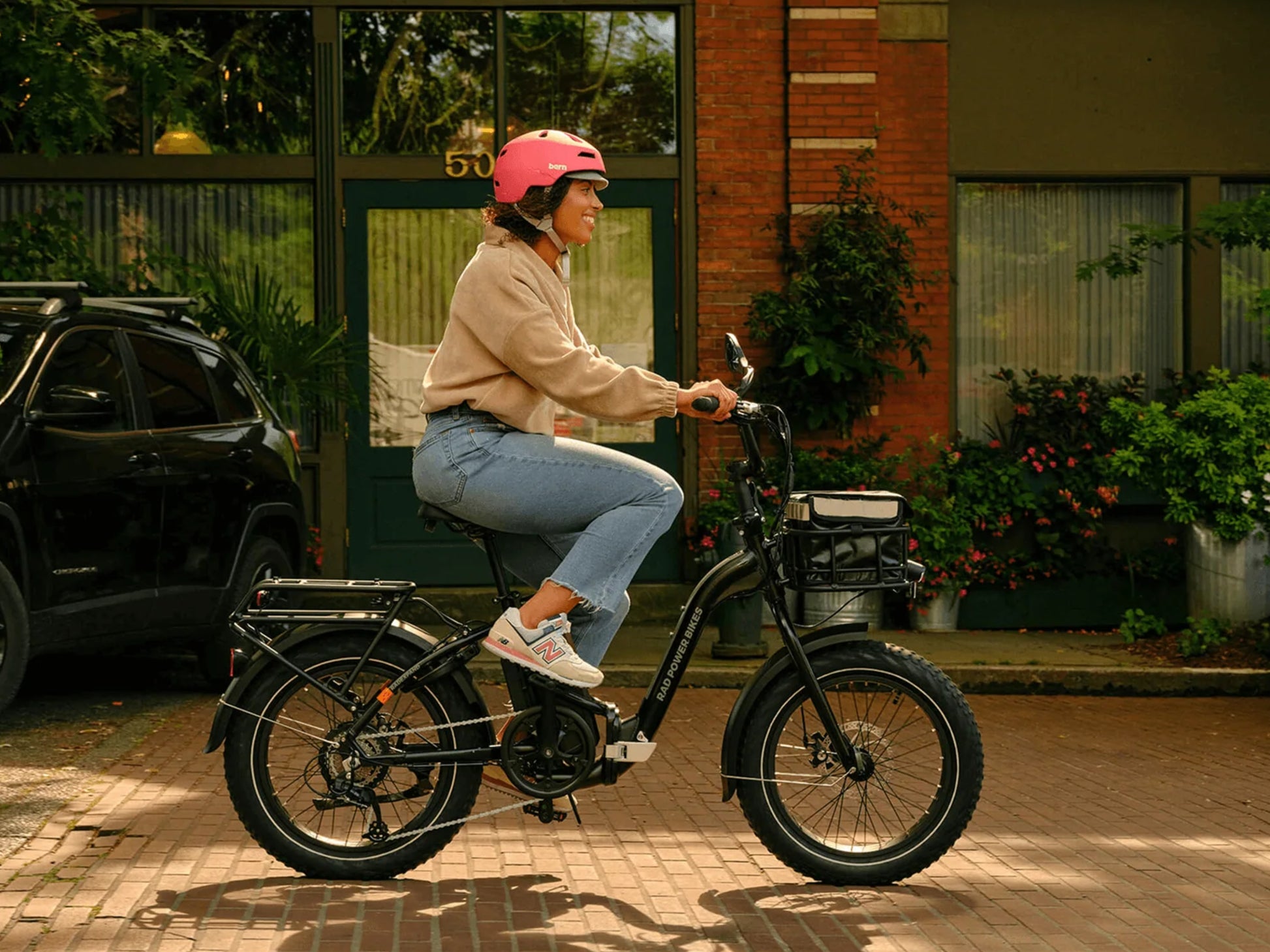 Rad Power RadExpand™ 5 Electric Folding Bike. Woman riding on a brick street