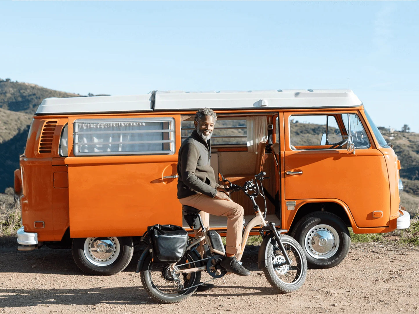 Rad Power RadExpand™ 5 Plus Electric Folding Bike Stone tan. Man parked on dirt next to an orange VW Bus.