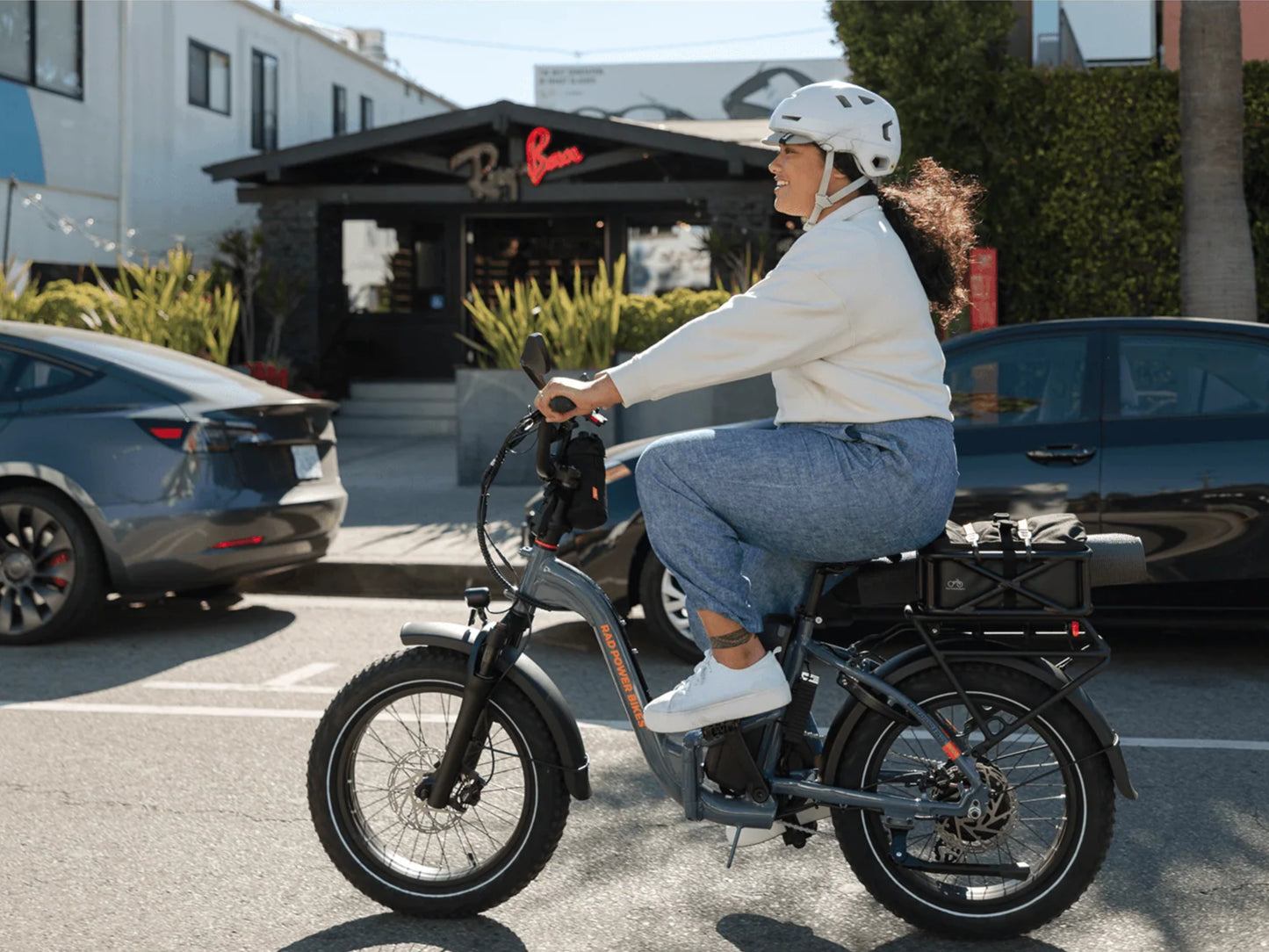 Rad Power RadExpand™ 5 Plus Electric Folding Bike Slate blue. Woman riding on street with cars and store in background.