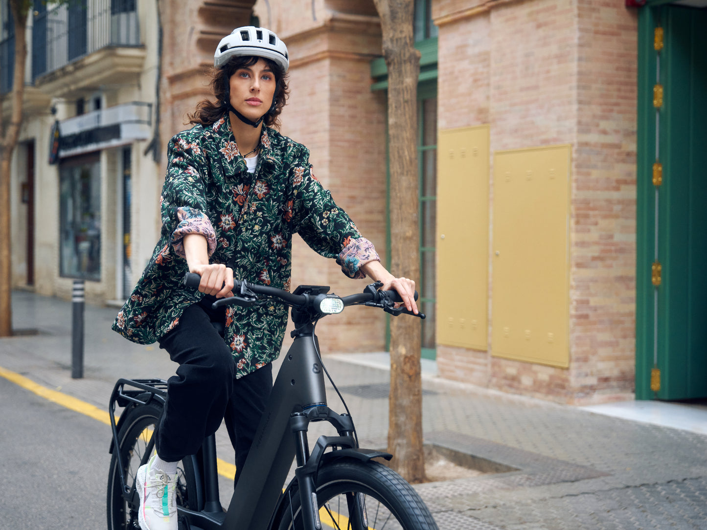 Riese and Muller Nevo5 Woman riding on city streets with brick buildings in background