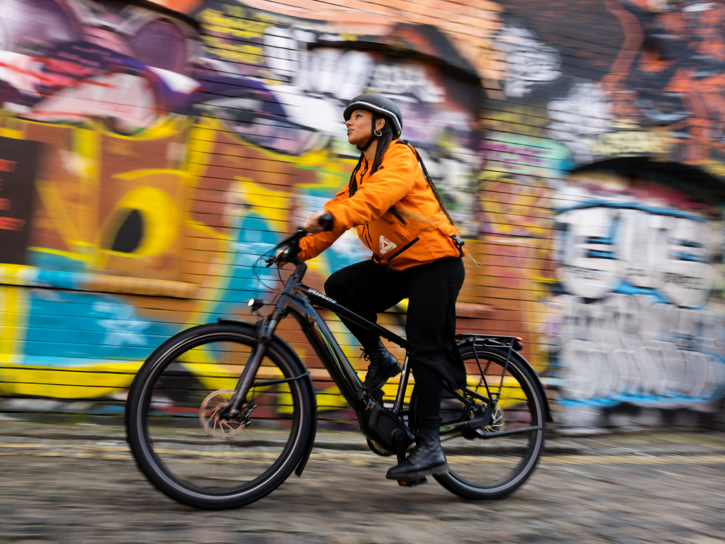 Specialized Turbo Vado Commuter eMTB hardtail. Woman riding in front of a graffiti wall