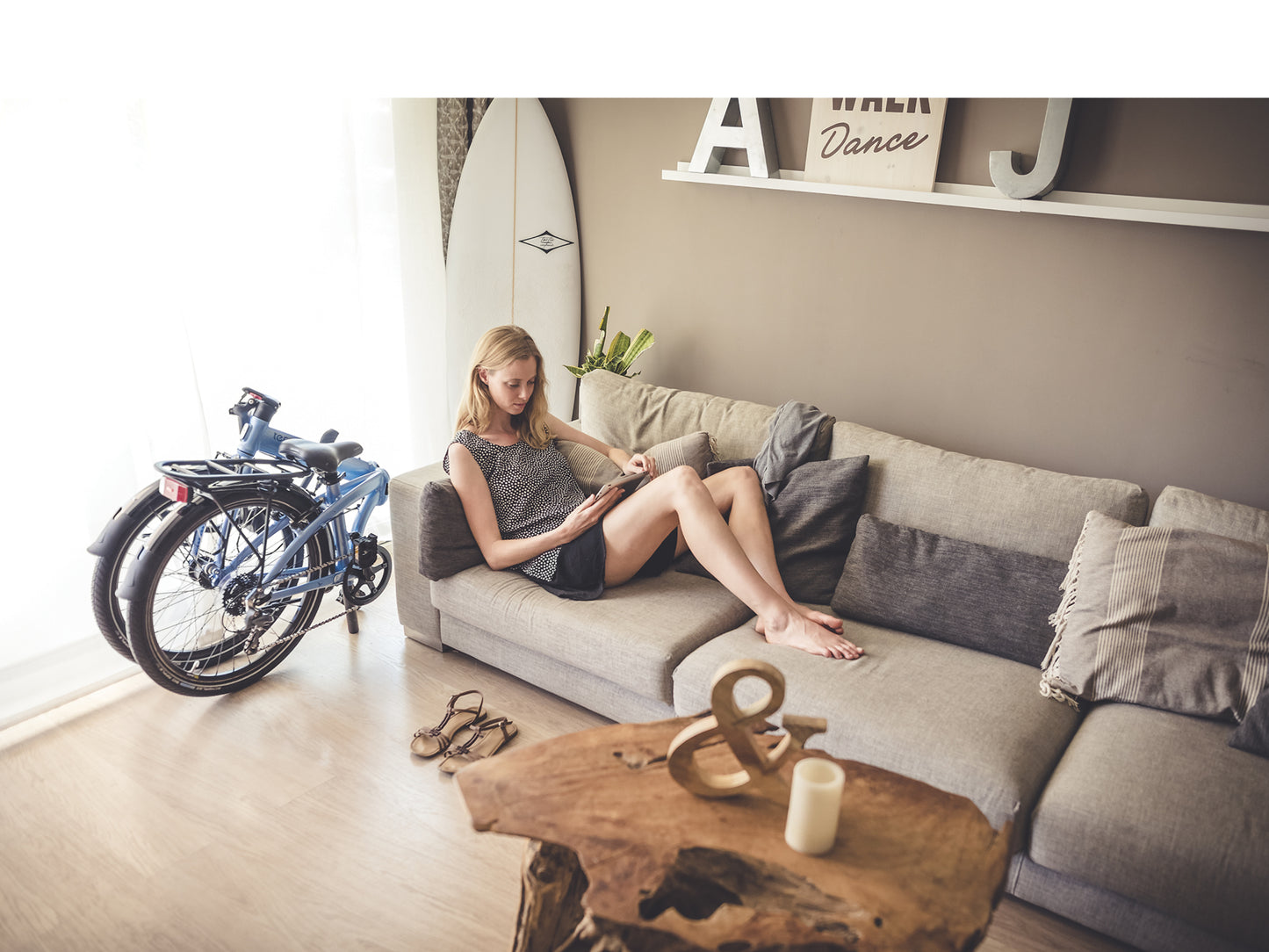 Tern Node folding bike. Folded and stored in an apartment setting. Woman relaxing on sofa