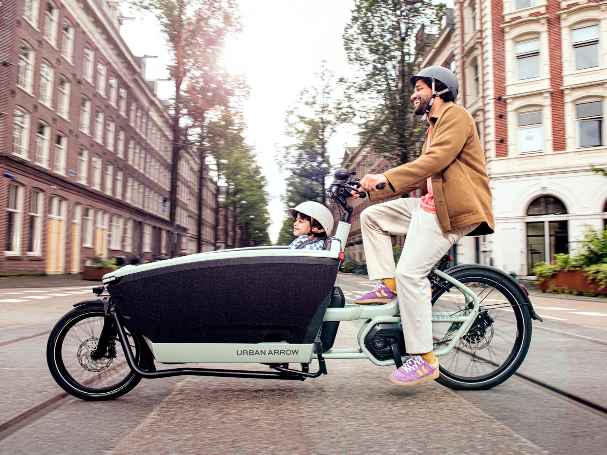 Urban Arrow Family Next Pro Electric Cargo Bike Green / black Lifestyle. Man and child on city street