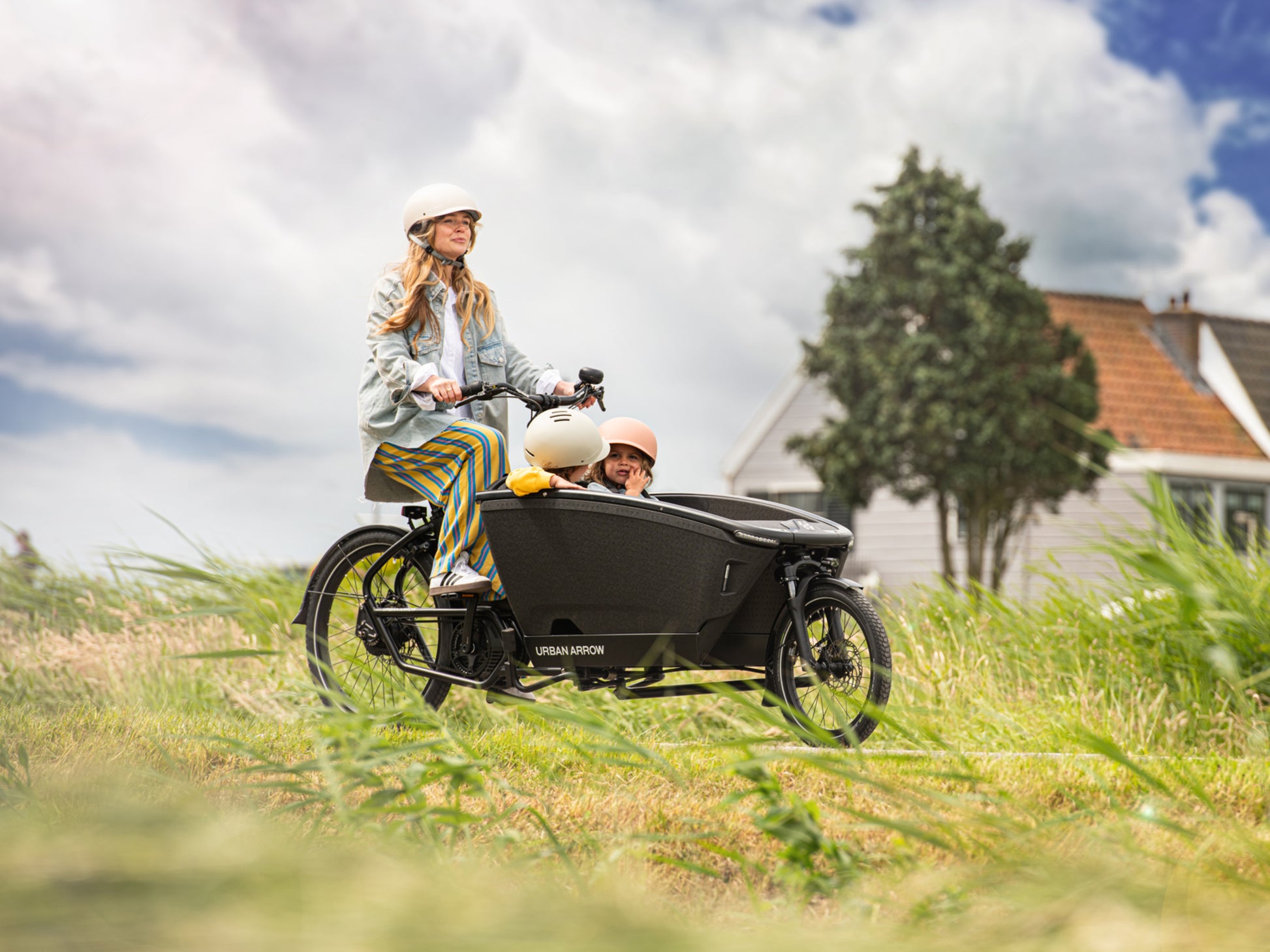 Urban Arrow Family Next Pro Electric Cargo Bike Green / black Lifestyle. Woman and children on county path