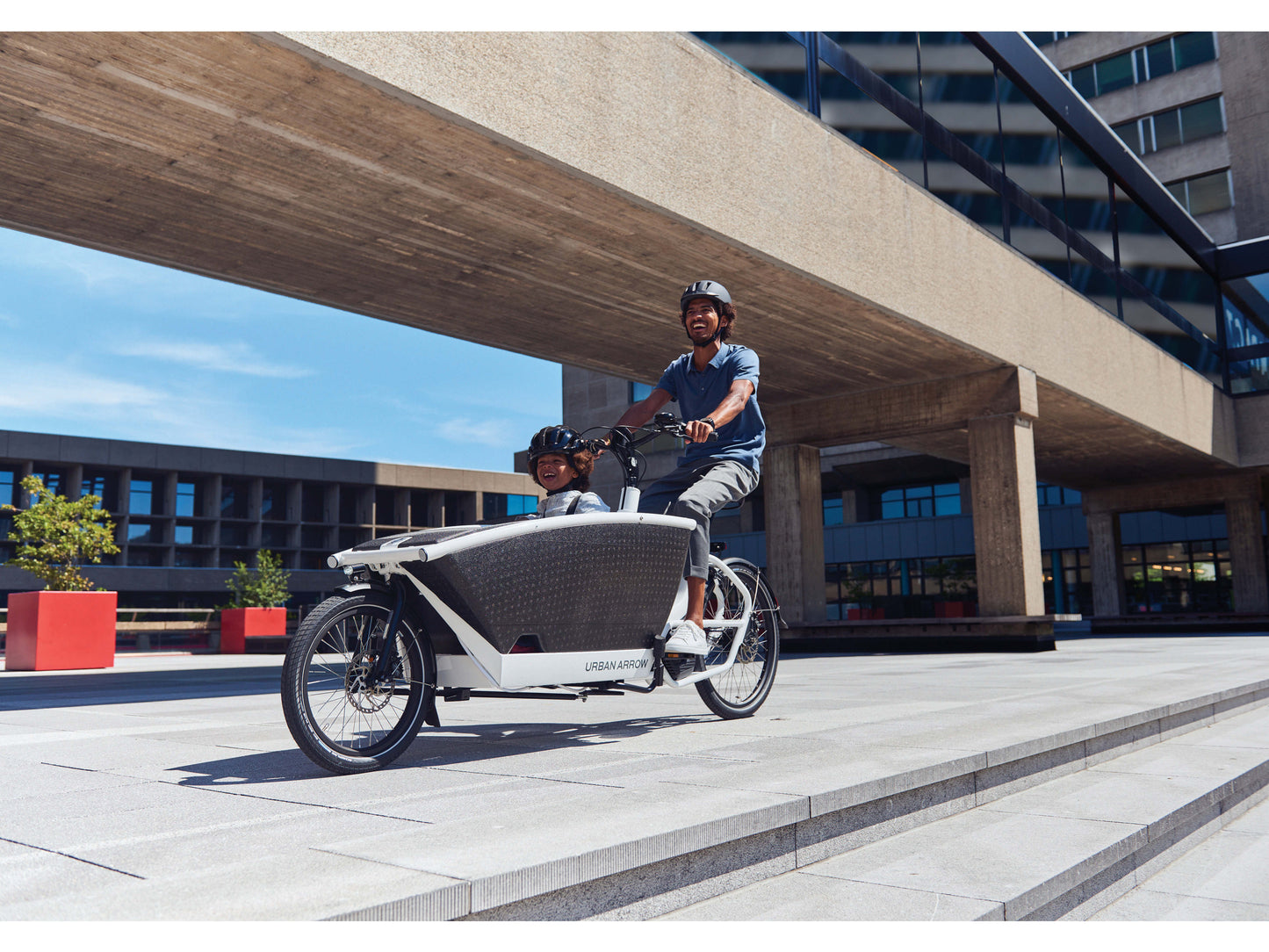 Urban Arrow Family Performance cargo electric bike man riding city path with child in front