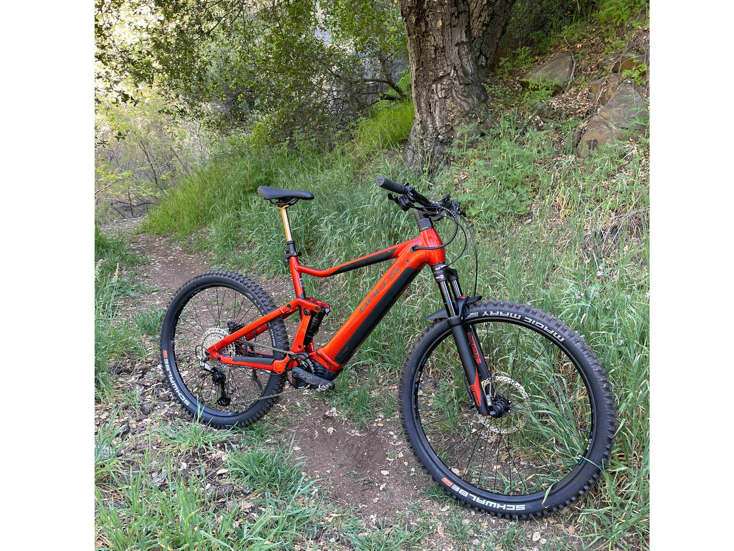 Bulls Copperhead EVO AM 4 750 eMTB full suspension metallic orange black matte front side profile on forest trail