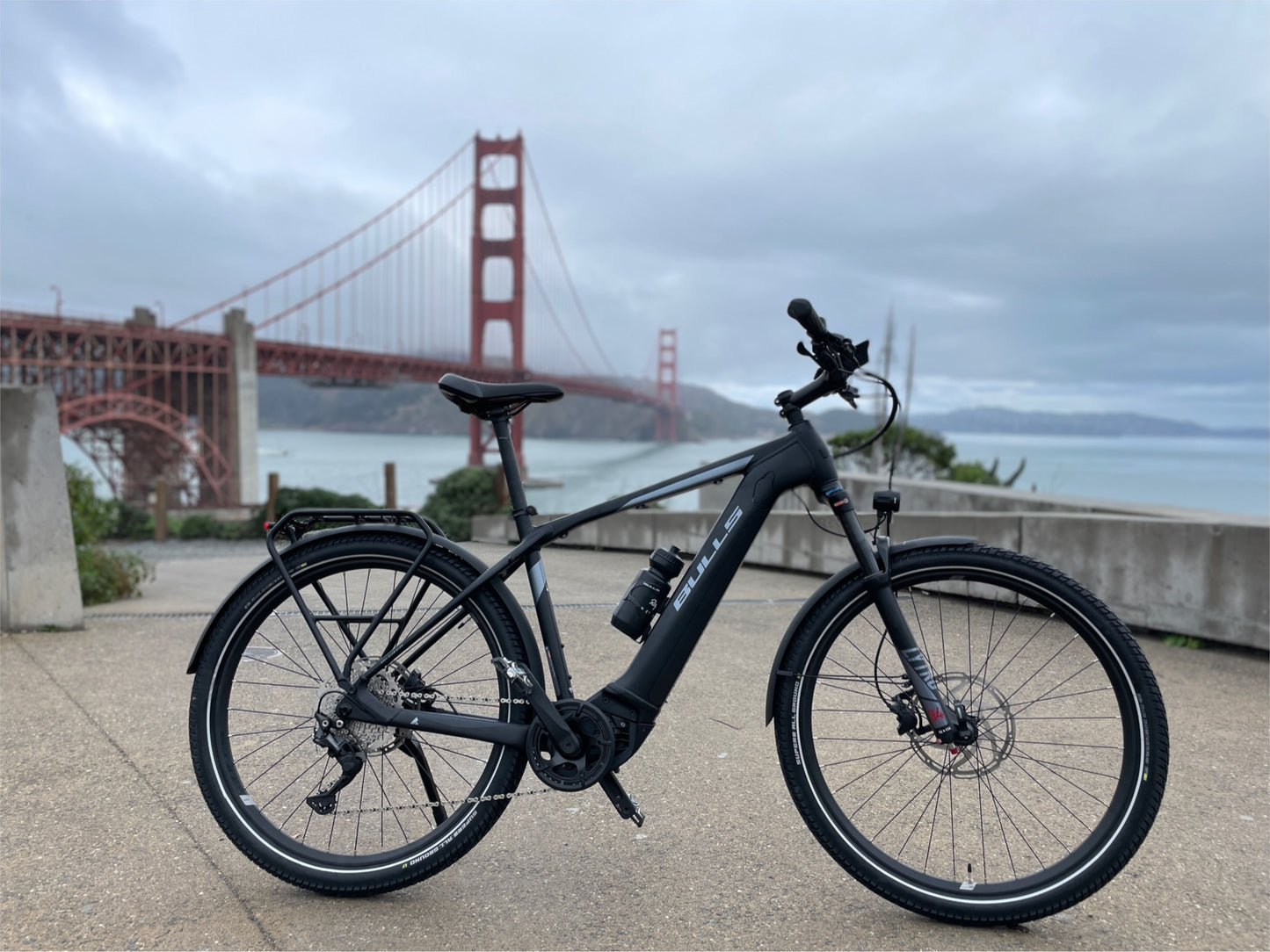 Bulls Iconic EVO 2 Speed eMtb hard tail Chrome Sapphire side profile with city bridge in background