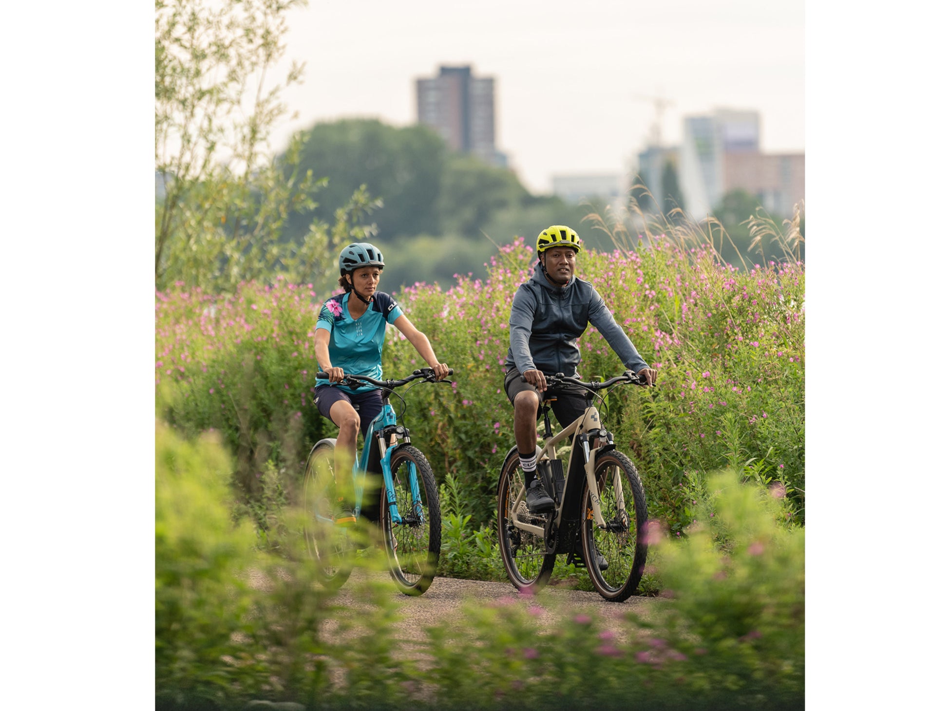 Cube Nuride Hybrid Performance 500 Allroad Easy Entry eMTB hardtail two people riding on trail with city in background