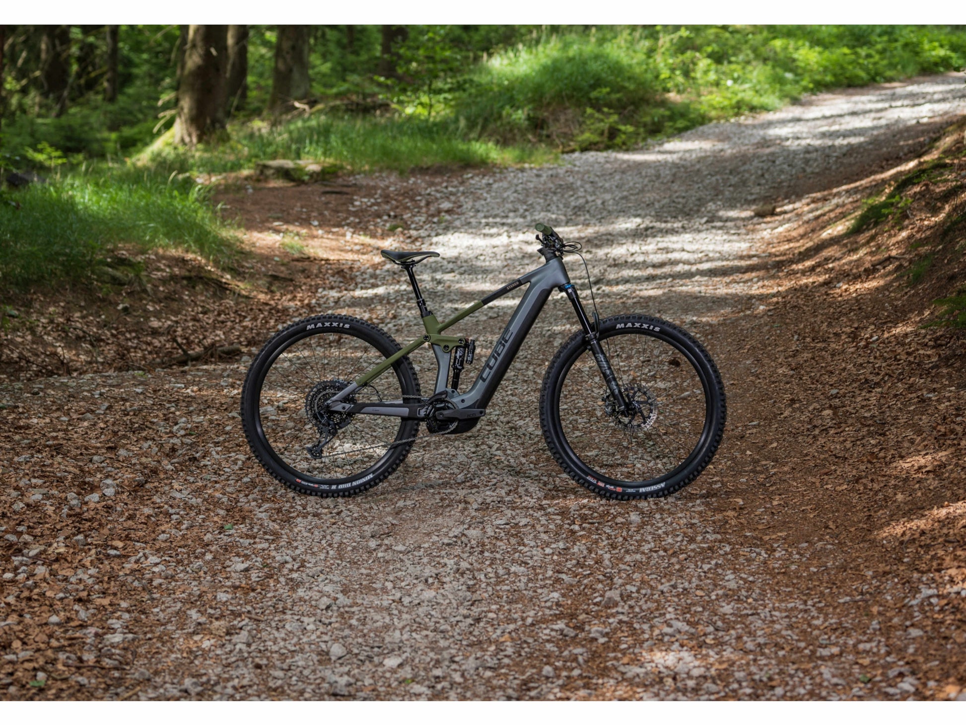 Cube Stereo Hybrid 140 HPC TM 750 eMTB full Suspension flashgrey n olive side profile forest trail background