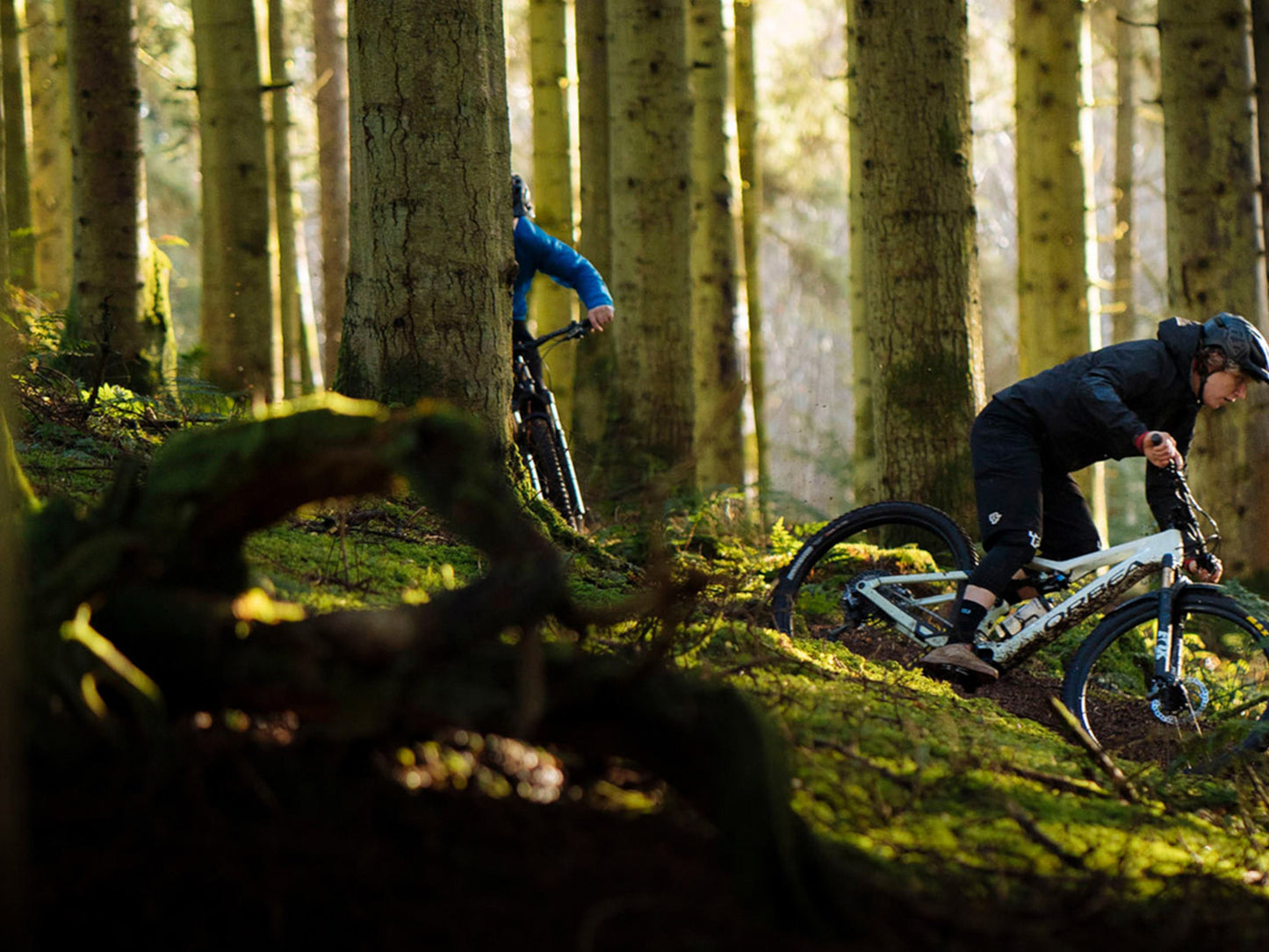 Two men riding Orbea Rise SL H30 e-mountain bikes in the trees