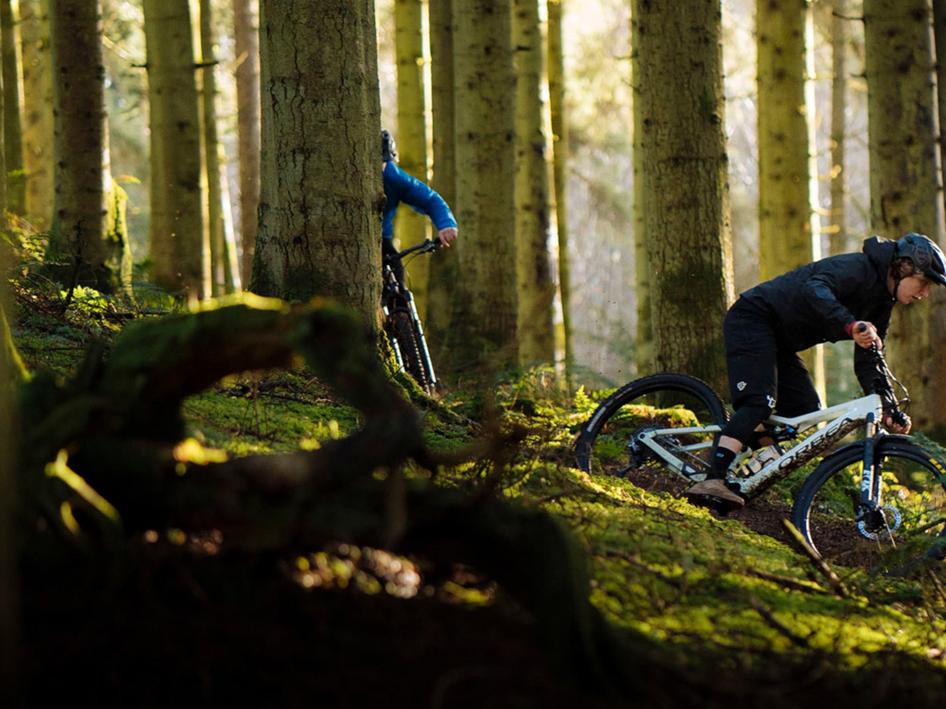 Two men riding Orbea Rise SL H30 e-mountain bikes in the trees