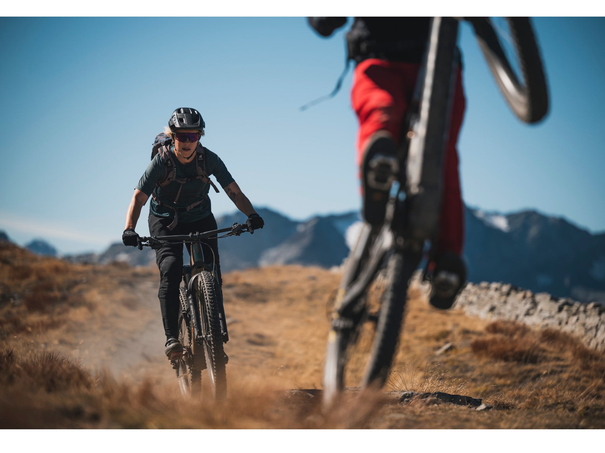 Orbea Rise M-LTD eMTB full suspension two people riding down single track mountains in background