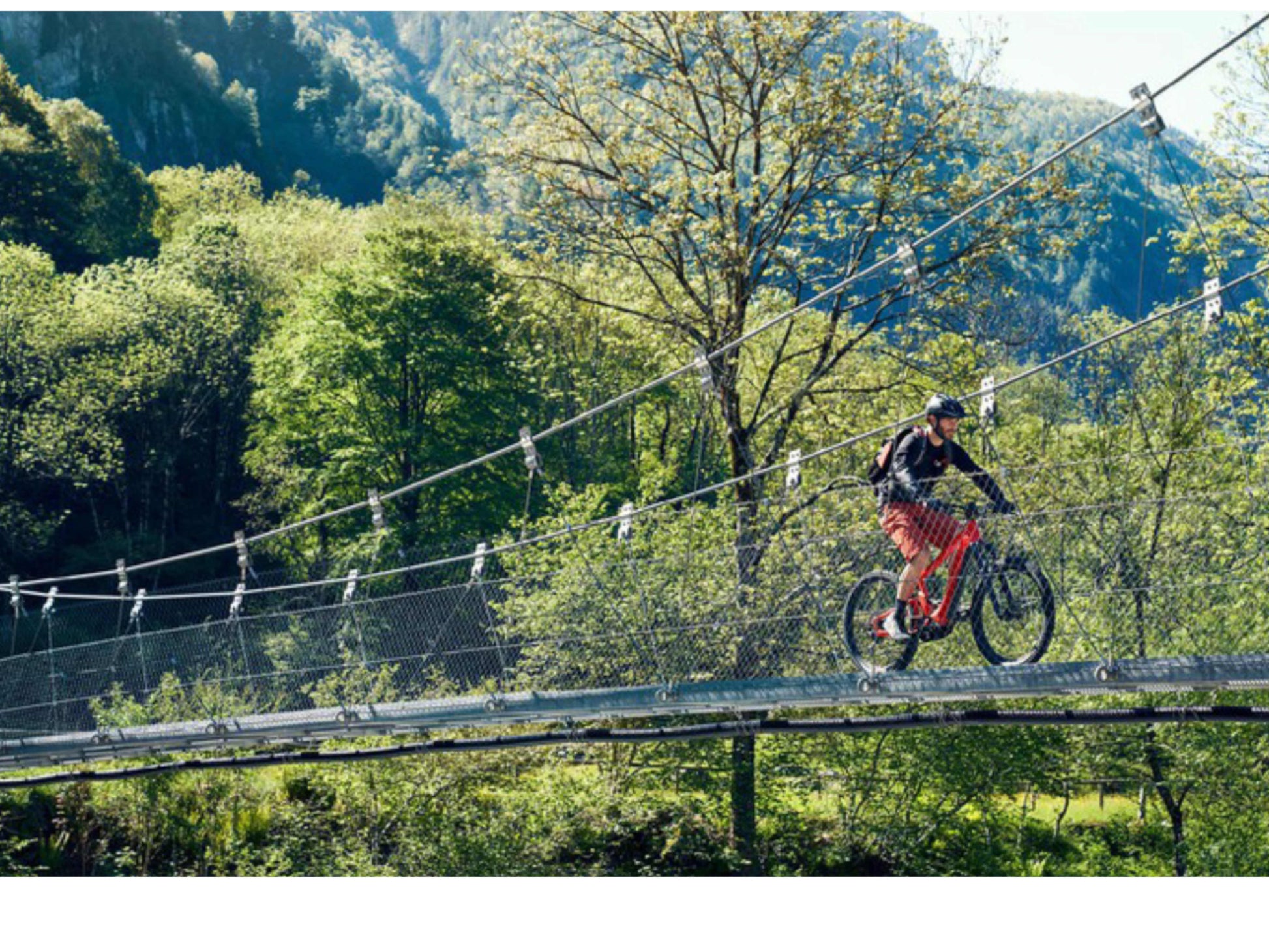 Riese and Muller Delite Mountain Touring eMTB full suspension man riding across old wooden bridge