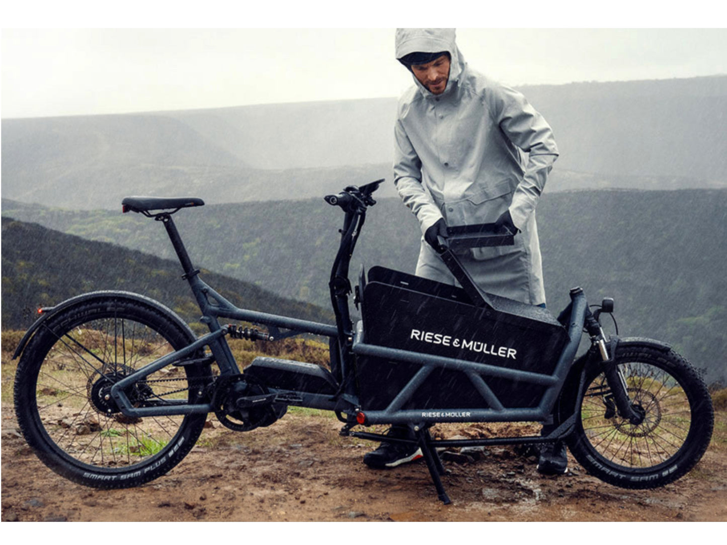 Riese and Muller Load 60 Touring HS eMTB full suspension man covering cargo area in rain storm
