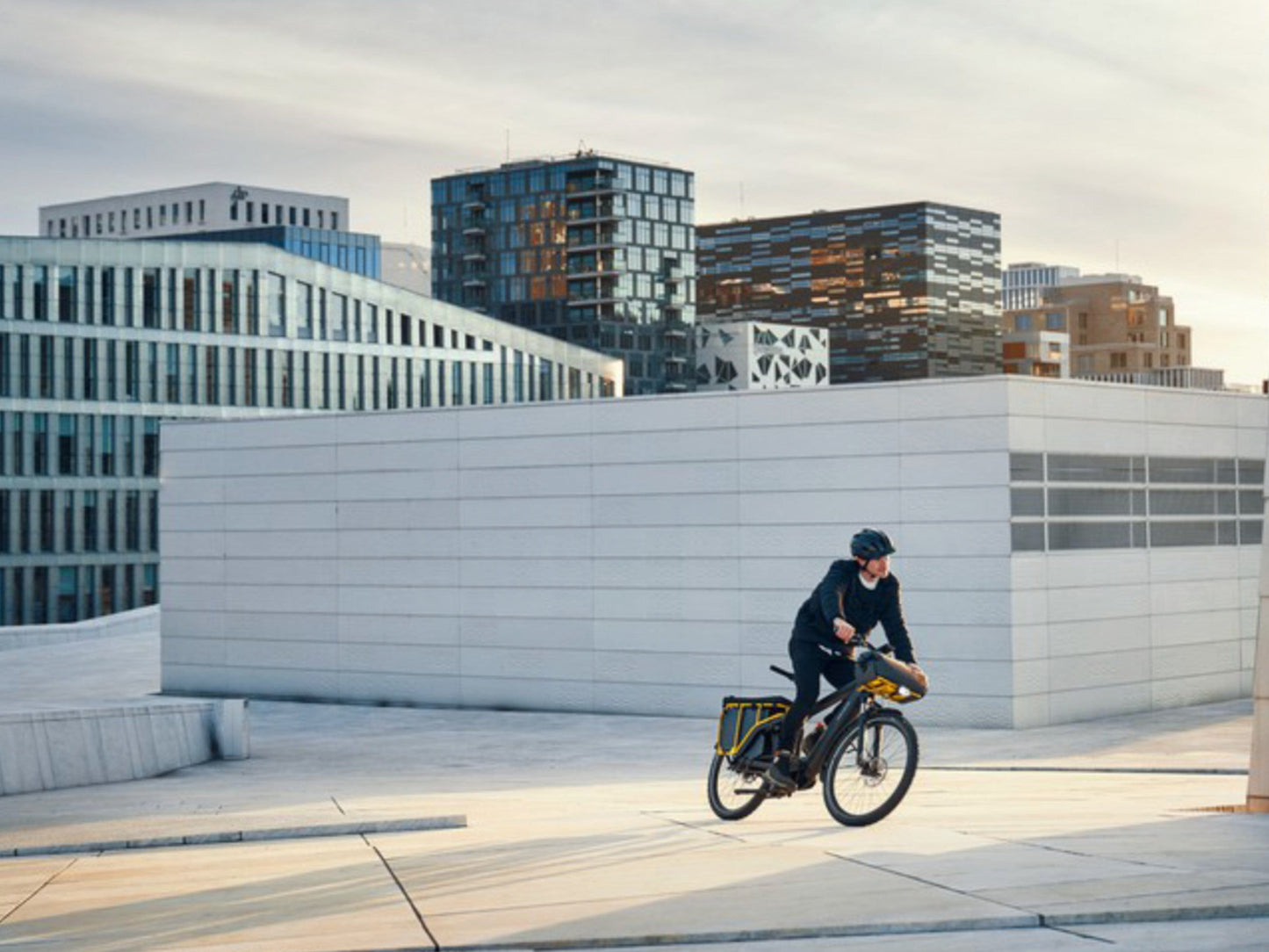 Riese and Muller Multicharger GT Touring HS emtb hardtail grey curry man riding through city plaza