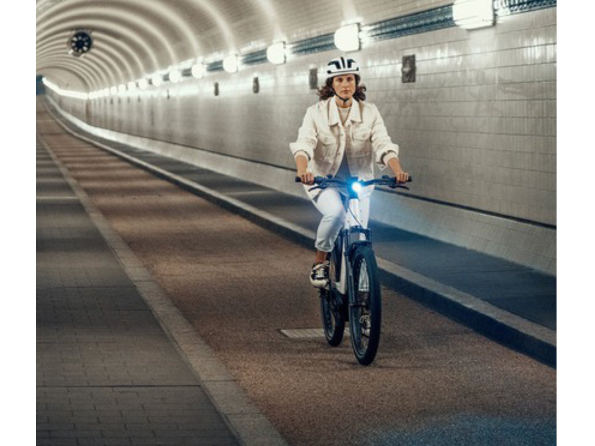 Riese and Muller Nevo GT Touring emtb hardtail woman riding on city tunnel bike path headlight on