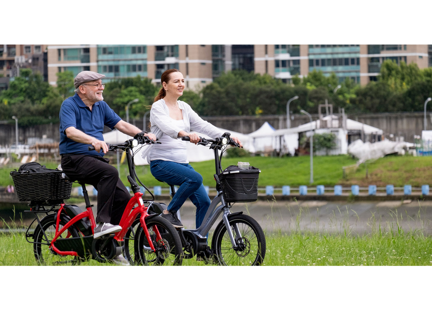 Tern NBD P8i electric cargo bike woman and man riding bike path park in background