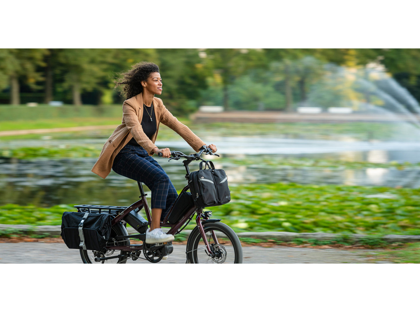 Tern Quick Haul D8 electric cargo bike woman riding on bike path with park in background