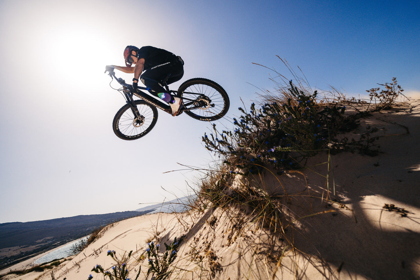 Mondraker Crusher Man rider getting air, jumping sandy hill