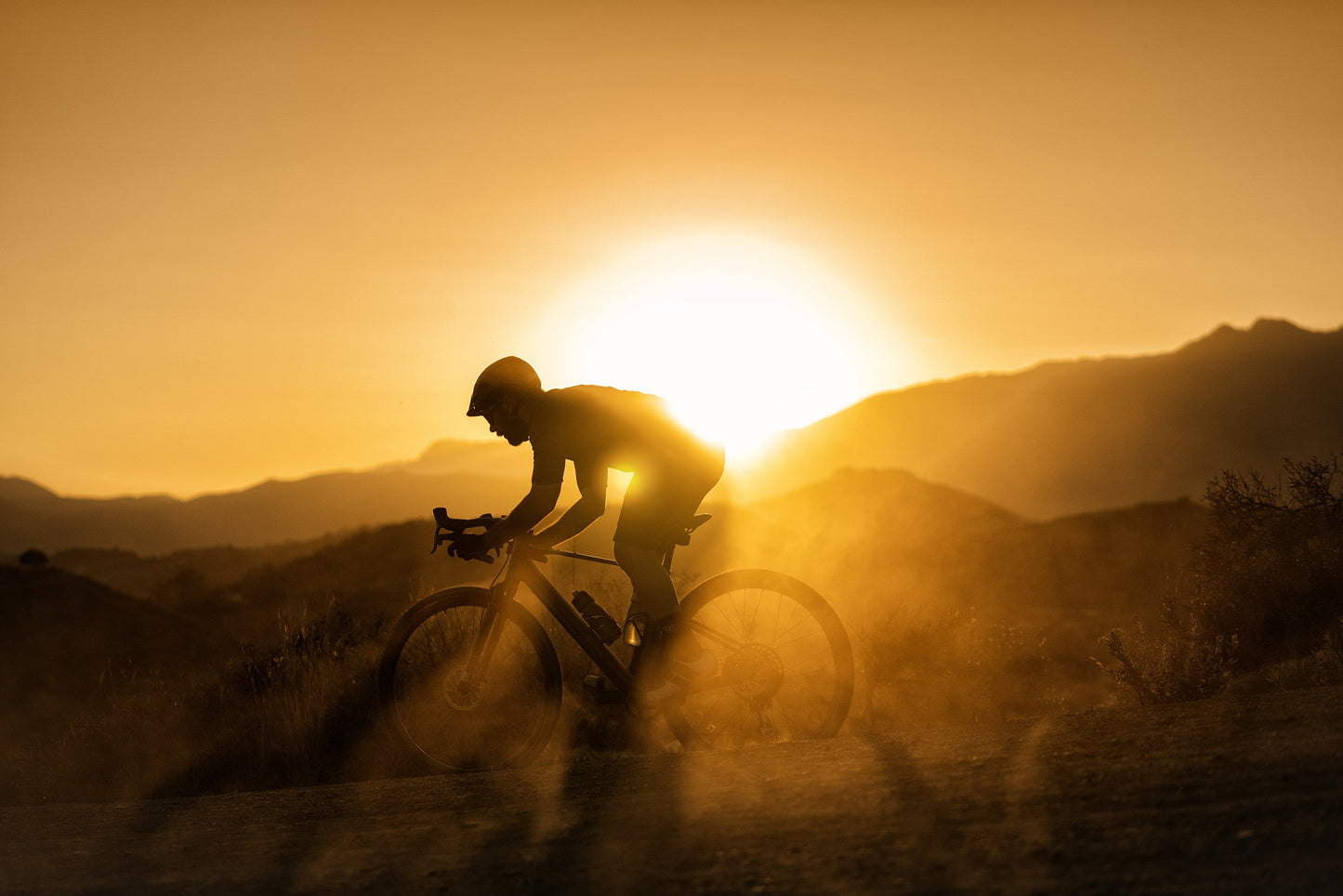 Mondraker Dusty Gravel electric bike Man riding at sunset with dust in the air
