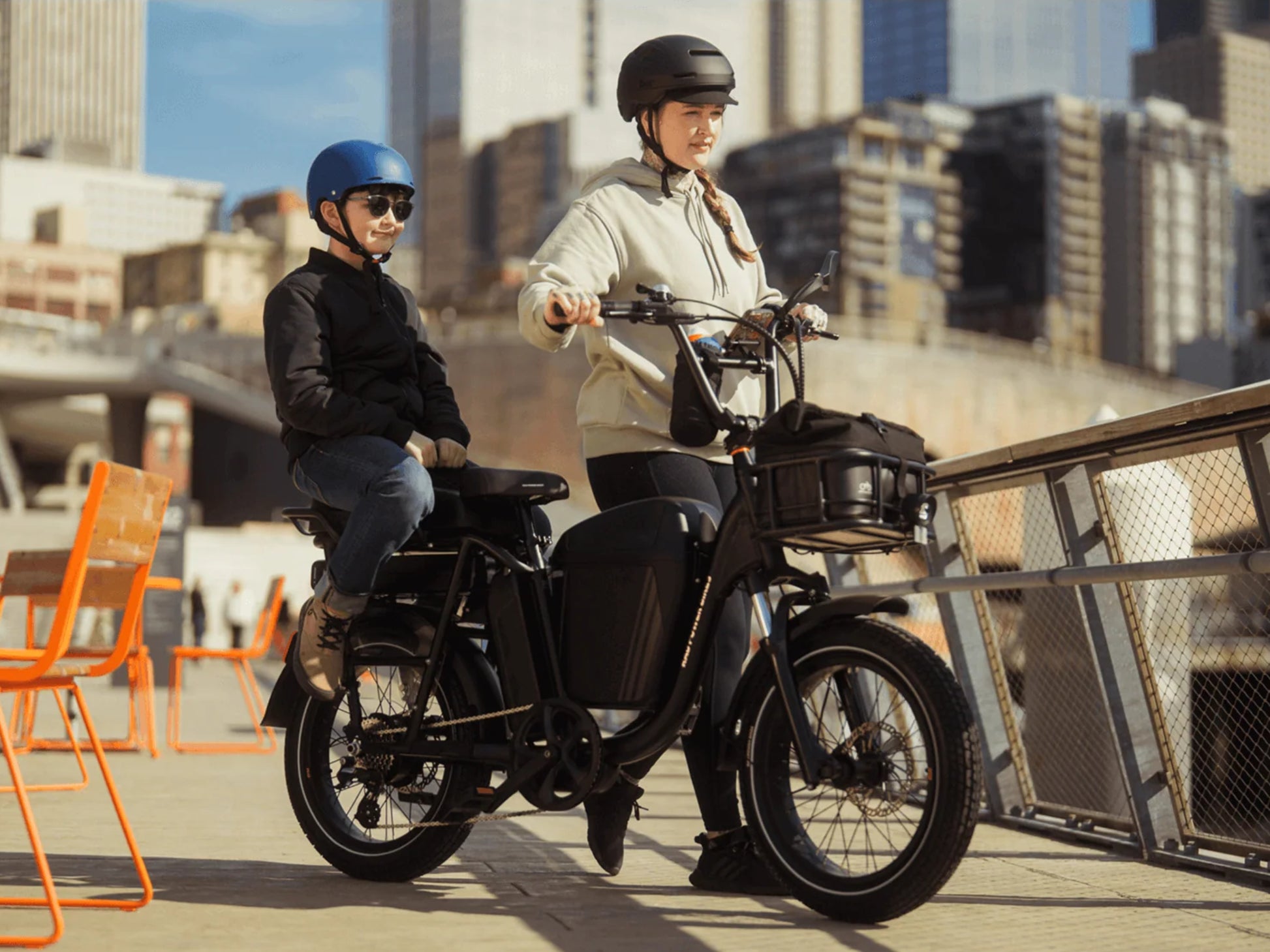 Rad Power RadRunner Plus Electric Cargo Utility Bike Matte black Woman and child on a ride in the city. Optional accessories shown.