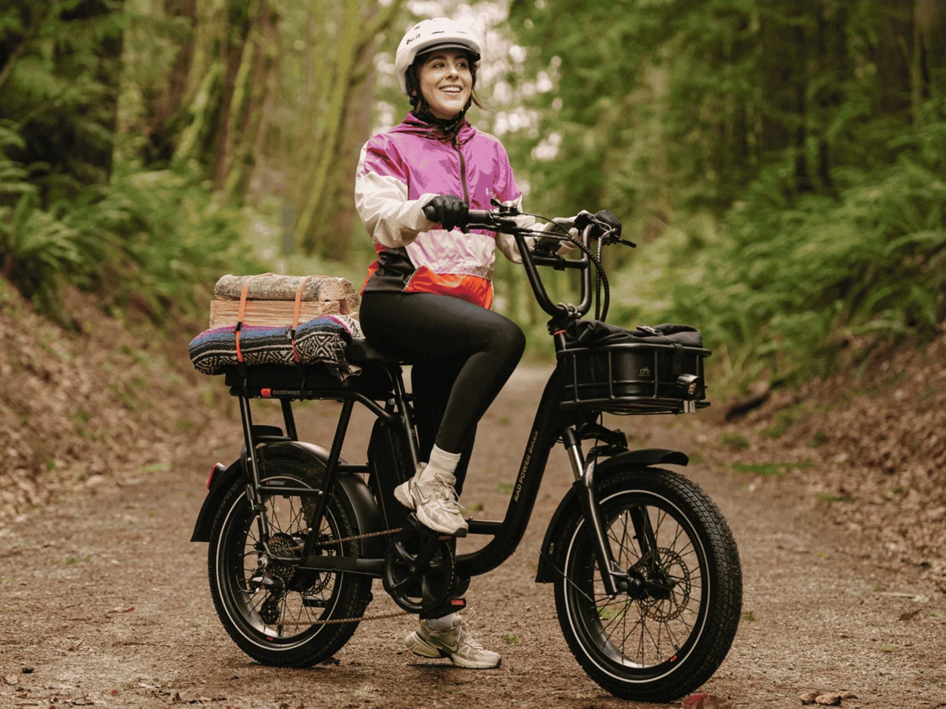 Rad Power RadRunner Plus Electric Cargo Utility Bike Matte black Woman on a forest trail, going to a campfire.