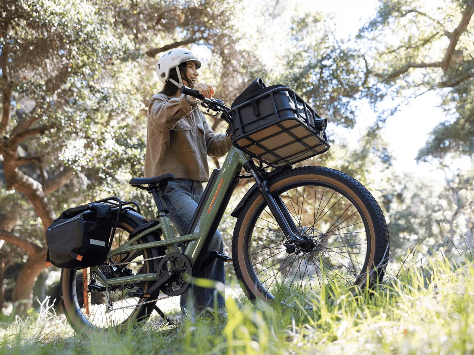 Rad Power Radster™ Trail Electric Off-Road Bike Fir green. Woman stopped offroad amongst the trees
