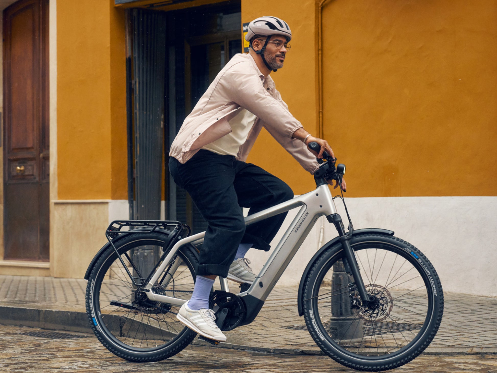 Riese & Muller Charger5 male rider on brick road with bright gold building in background