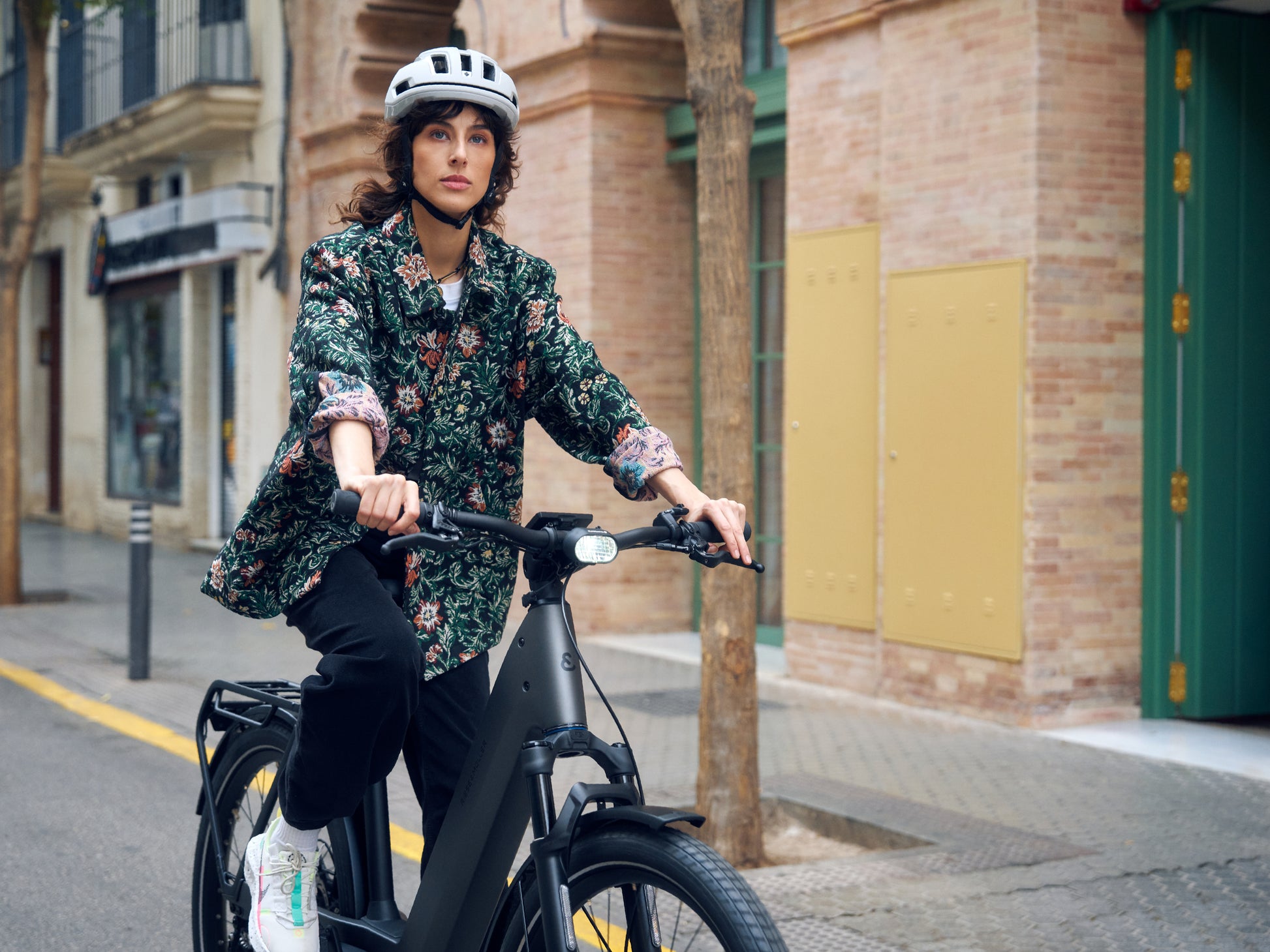 Riese and Muller Nevo5 Woman riding on city streets with brick buildings in background