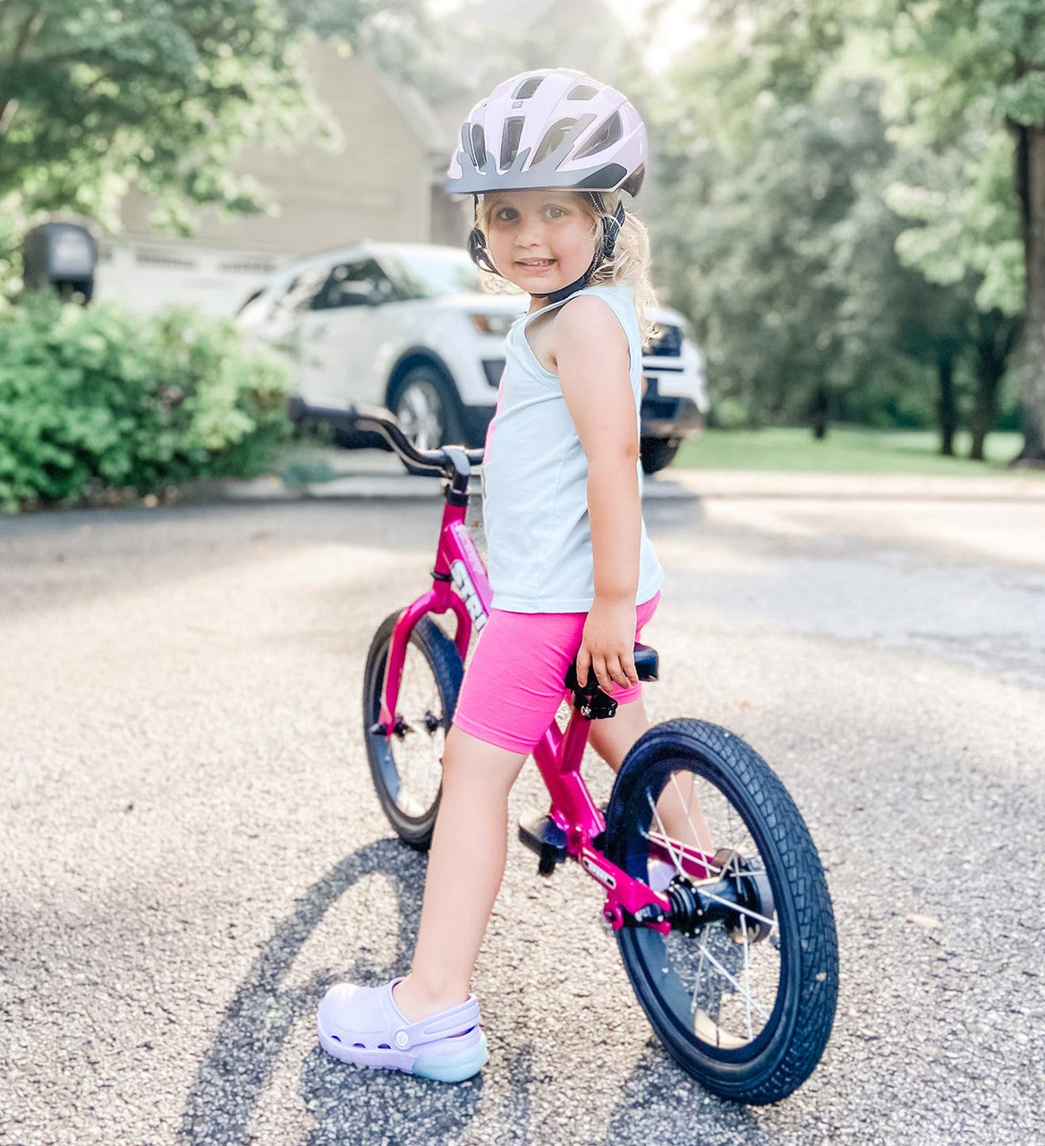 Strider 14x Convertible Bike Classic Fushcia Child striding on a residential street