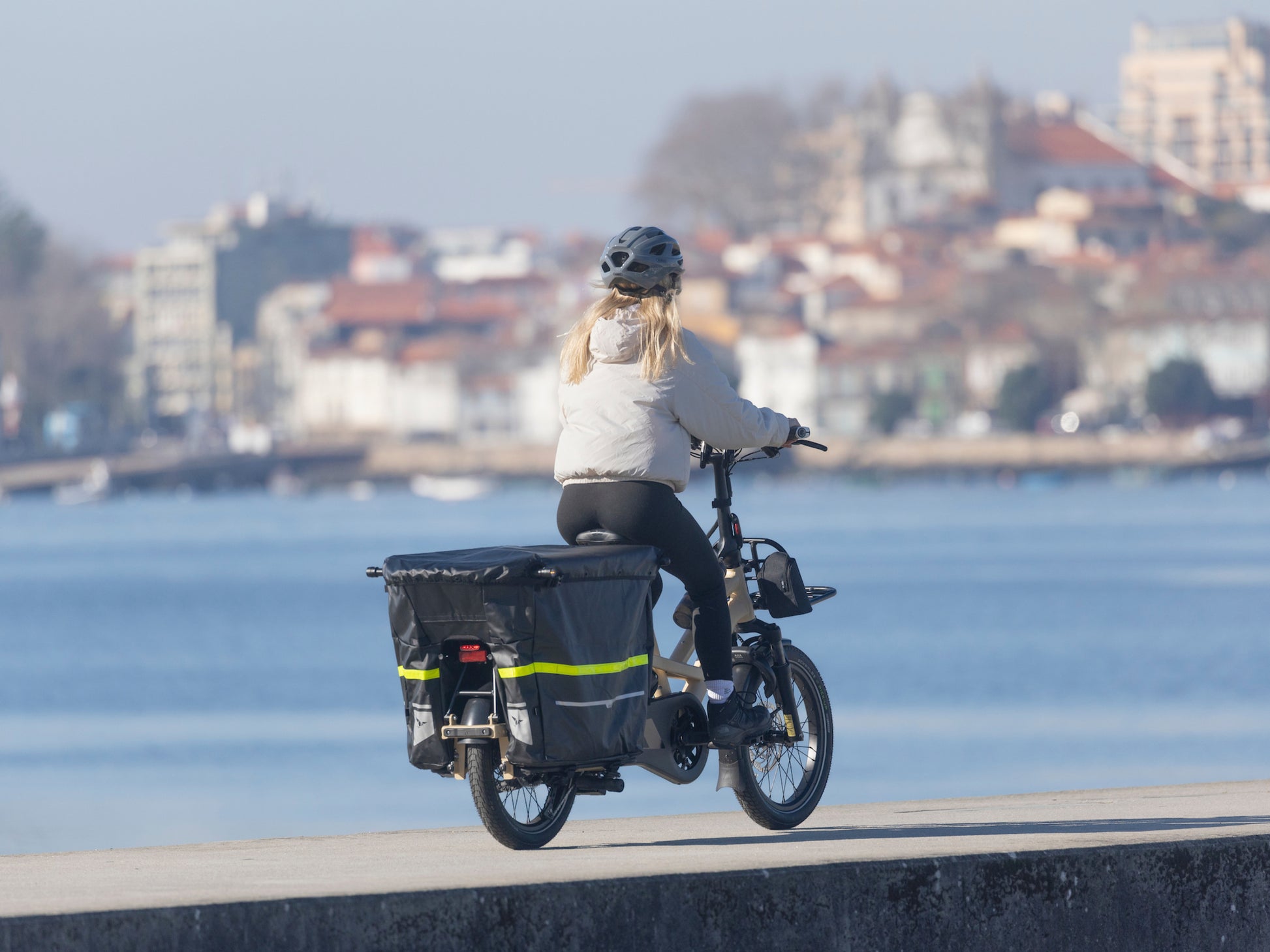 Tern GSD P00 Elecric, folding Cargo bike. Lifestyle, rider on waters ledge with City Scape background