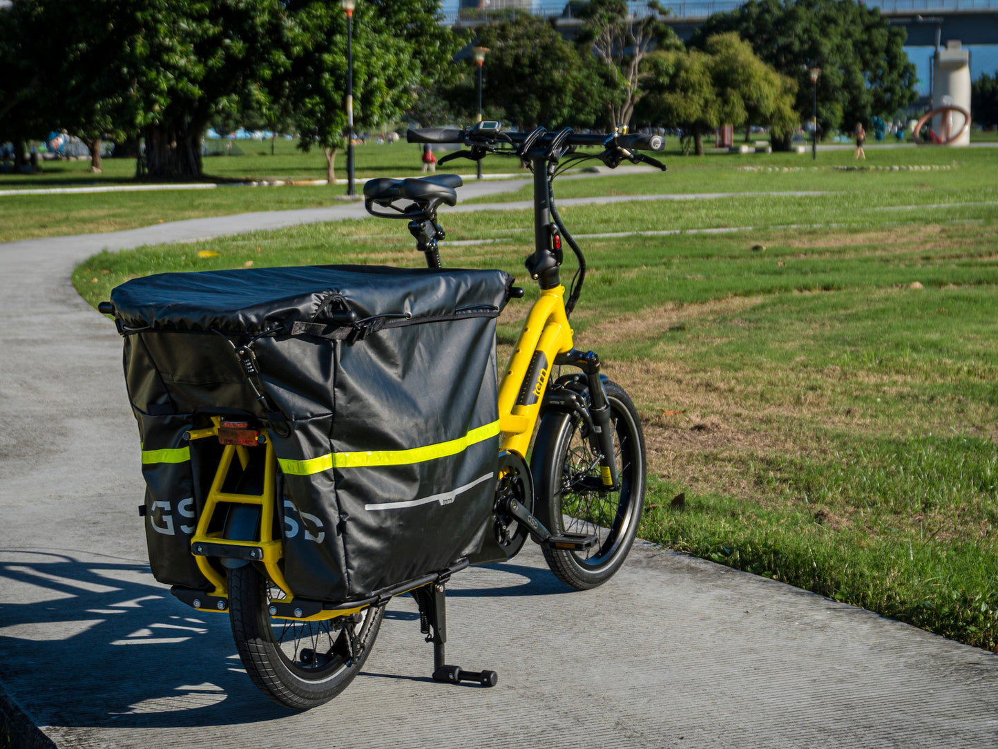 Tern Storm Box with Cargo Lid Lock installed on bike. Lifestyle in park, rear facing view
