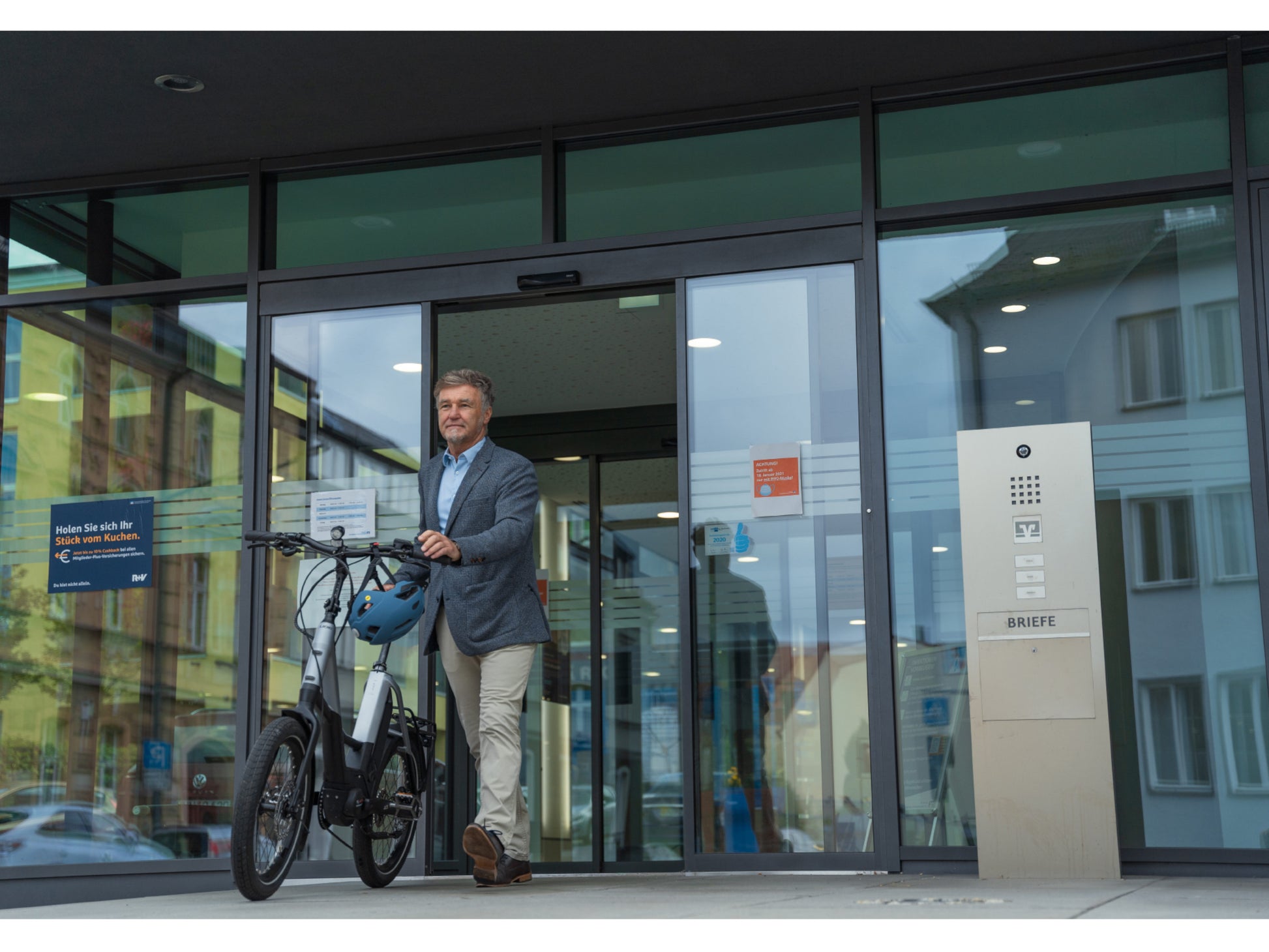 Cube Fold Sport Hybrid 500 electric bike businessman walking out of building with bike