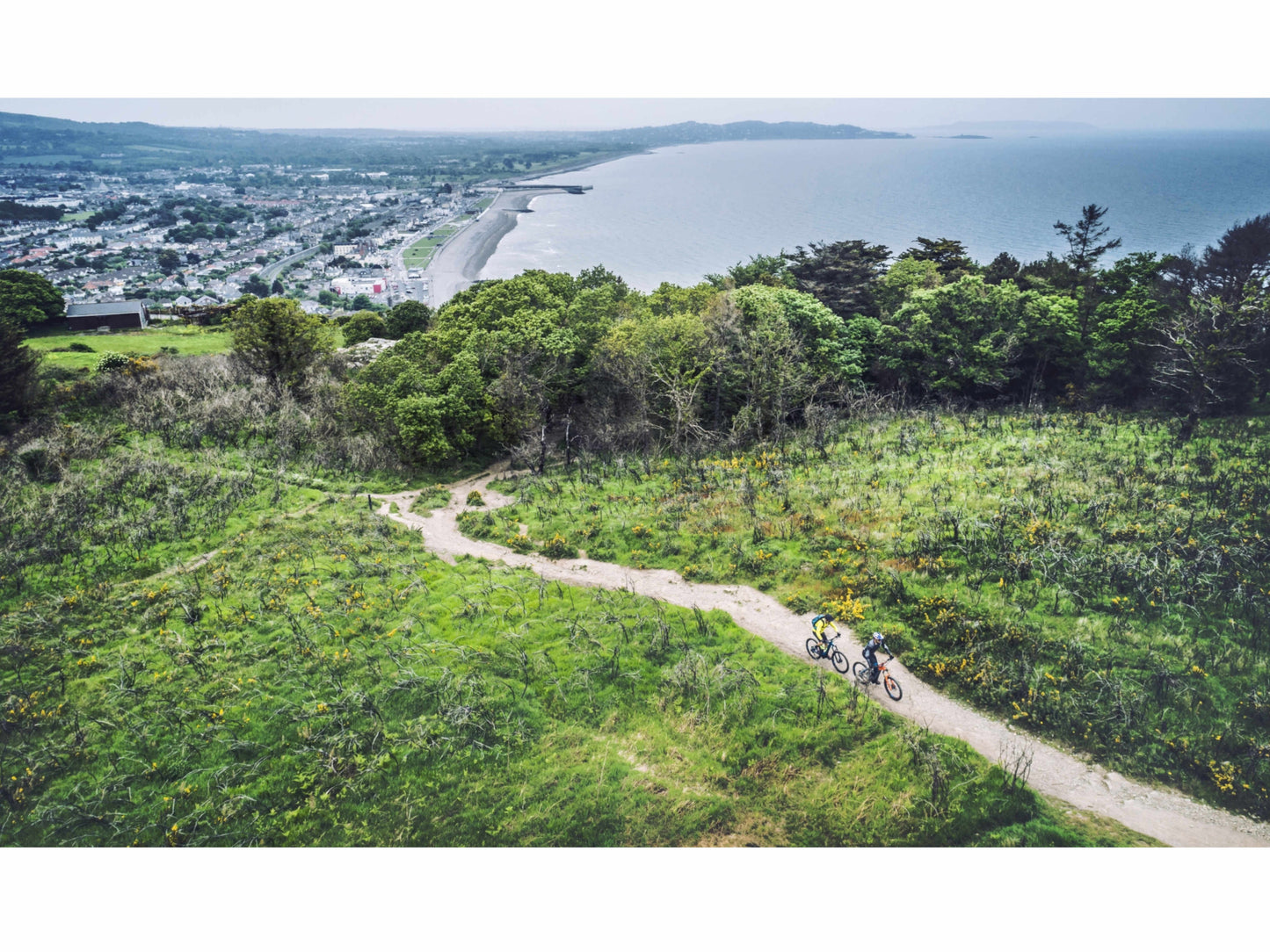 Cube Stereo Hybrid 120 PRO 625 eMTB full Suspension two people riding bike trail with ocean beach background