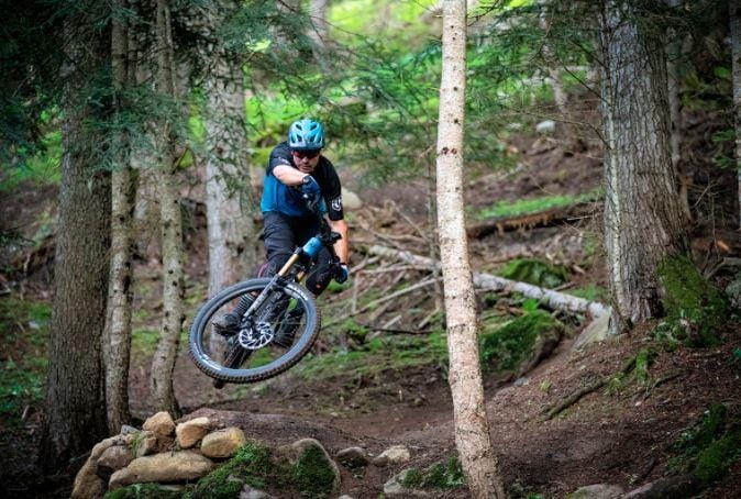Jumping a Mondraker Crafty SE electric mountain bike on a forest trail